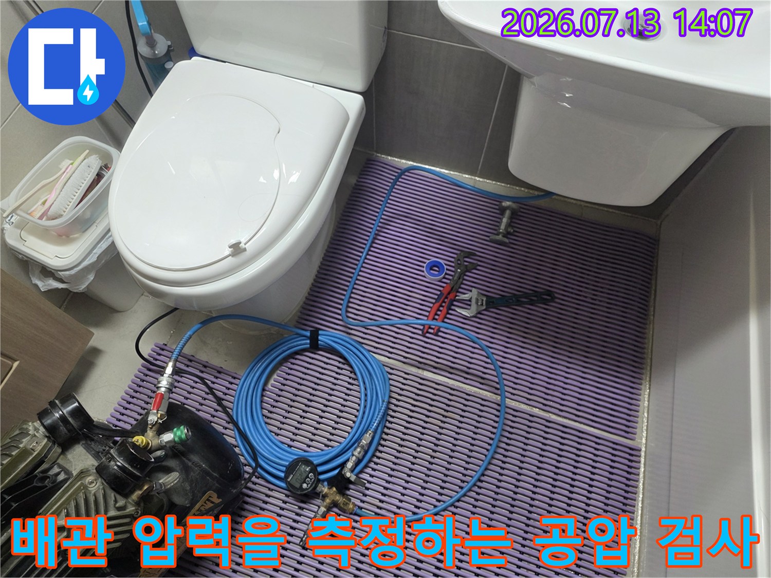 동그란 게이지와 파란색 호스를 연결해 화장실 내부 배관을 정밀 점검하는 모습