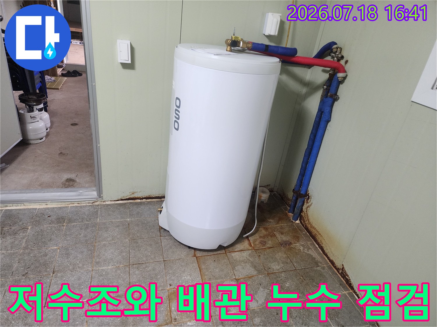 흰색 저수조 옆에 설치된 파란색과 빨간색의 금속 배관 시스템
