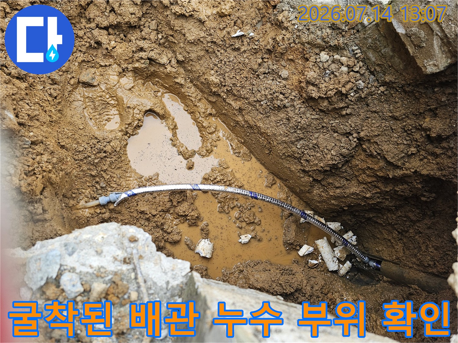 노출된 파란색 계량기 연결용 배관과 주변의 젖은 흙이 대조되는 누수 현장 사진