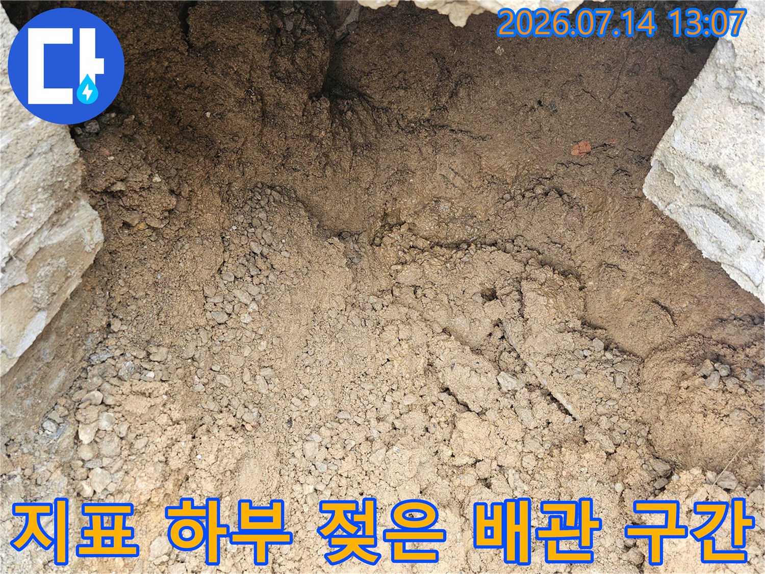 흙과 돌이 뒤섞인 토사 내 노출된 누수가 발생한 배관 부위