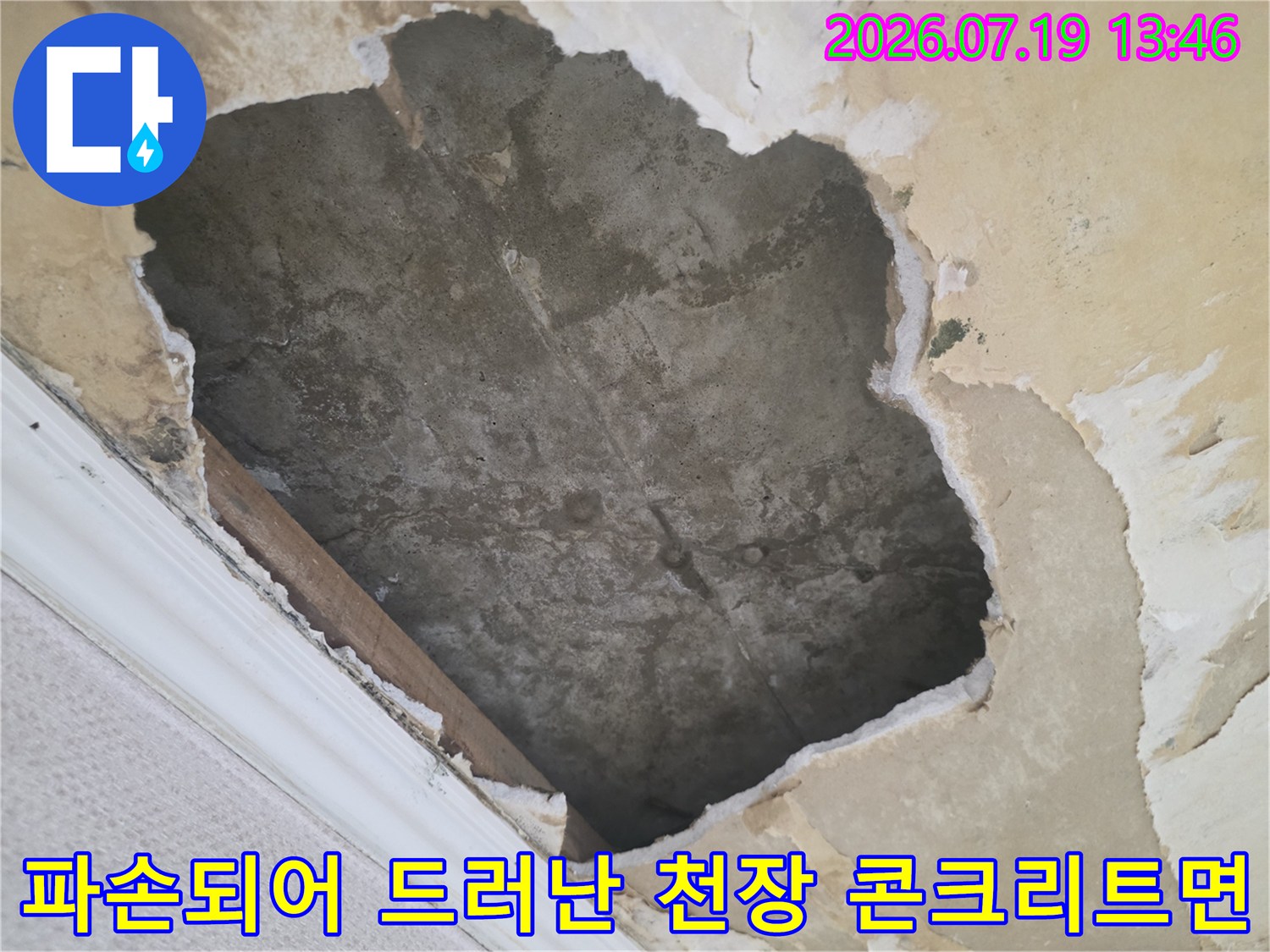 습기로 인해 변색된 회색 콘크리트 천장과 주변의 뜯어진 마감재 파편들