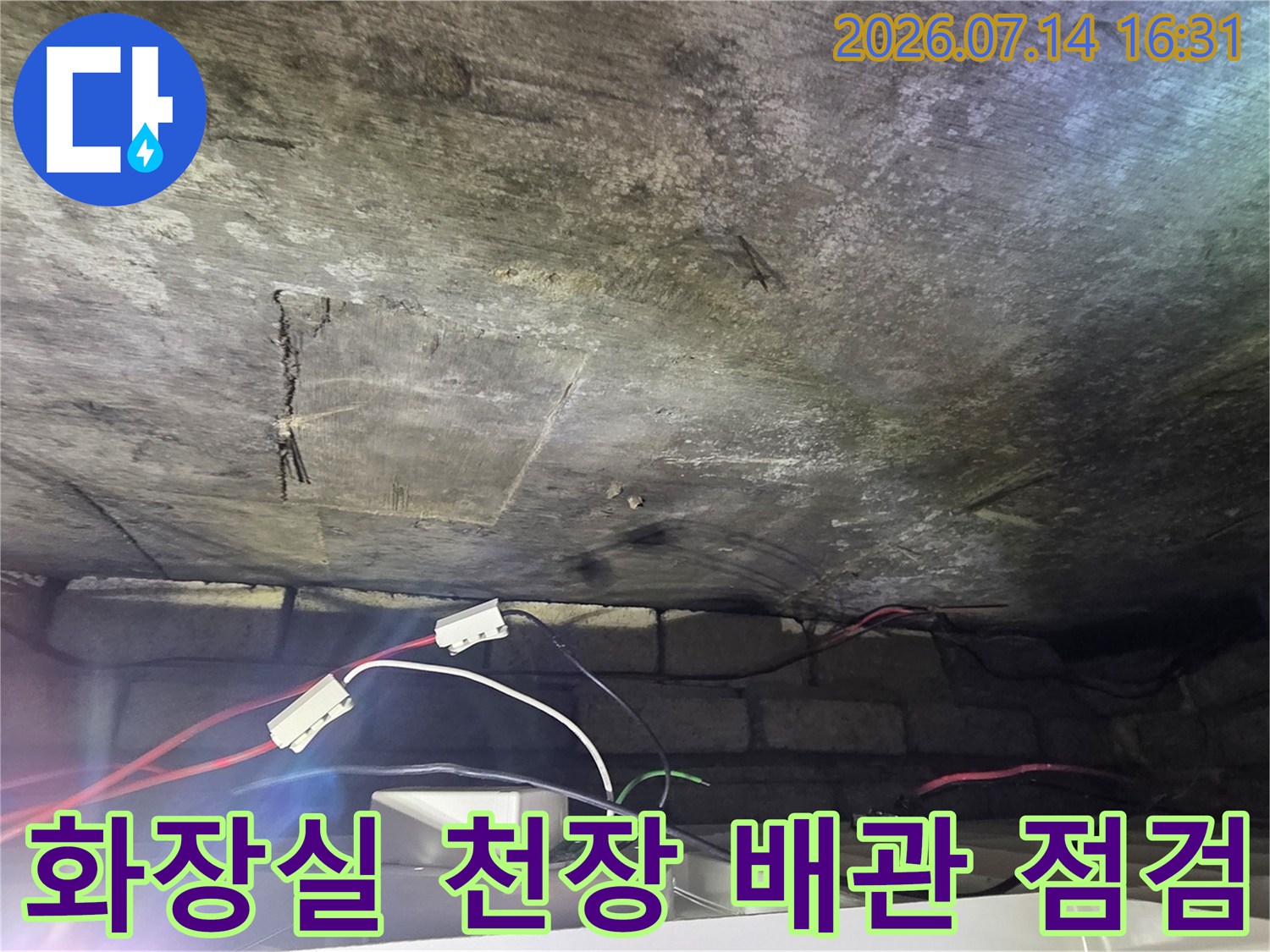 화장실 천장 내부의 노출된 배관과 공압 테스트용 연결 장비 모습