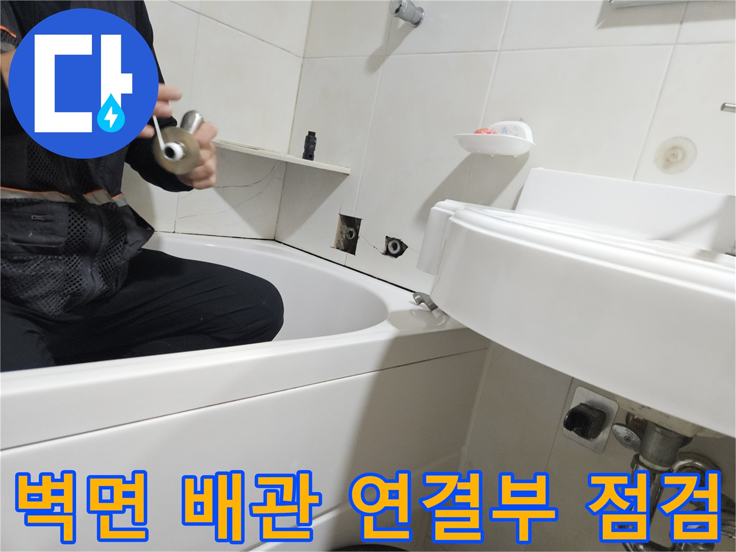 타일 벽면과 욕조 사이의 배관 부속 장비 확인 작업