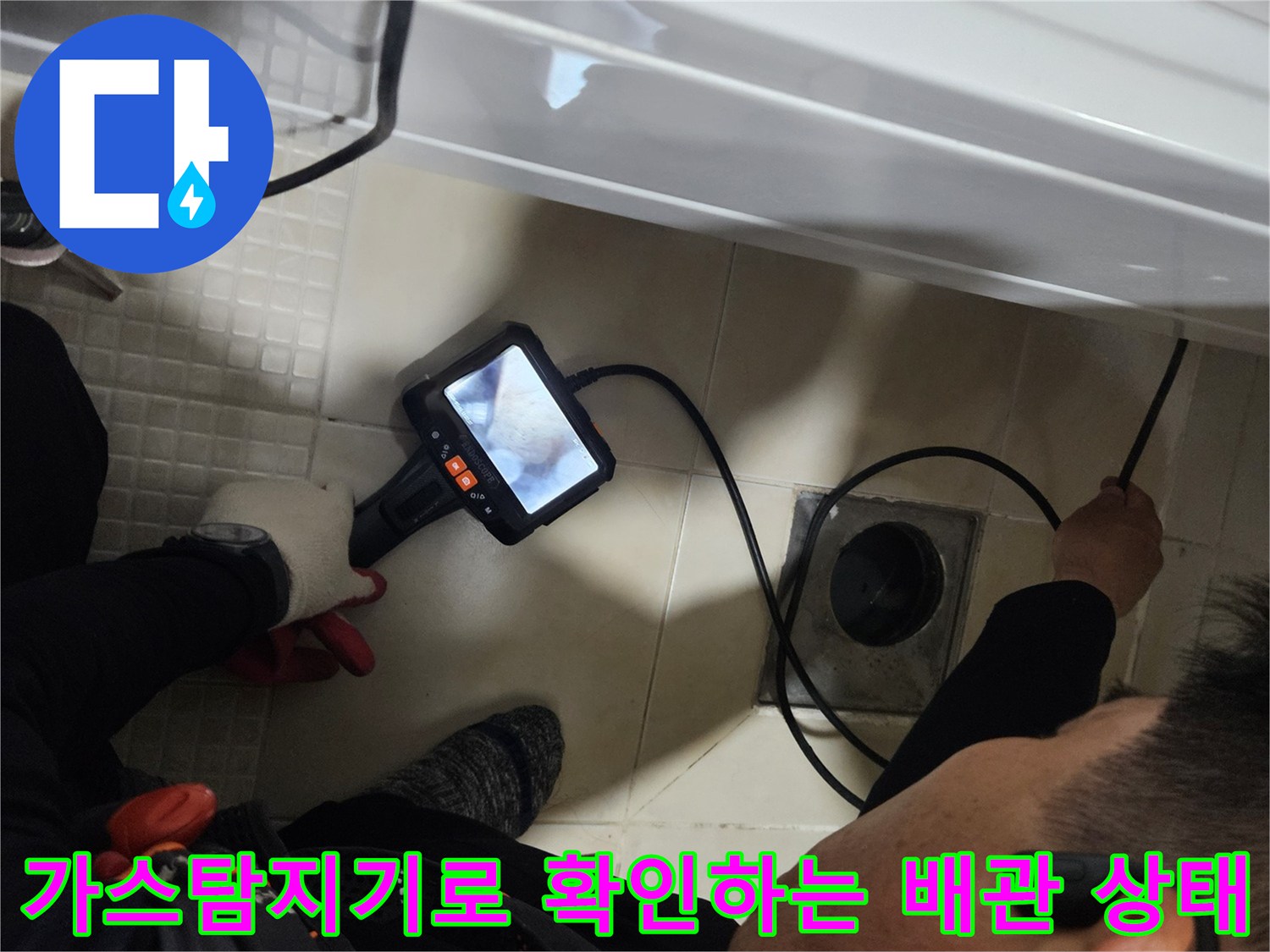 화장실 바닥 배수구 근처에서-가스 탐지기를 사용하여-배관의 누수 지점을 추적하는 모습