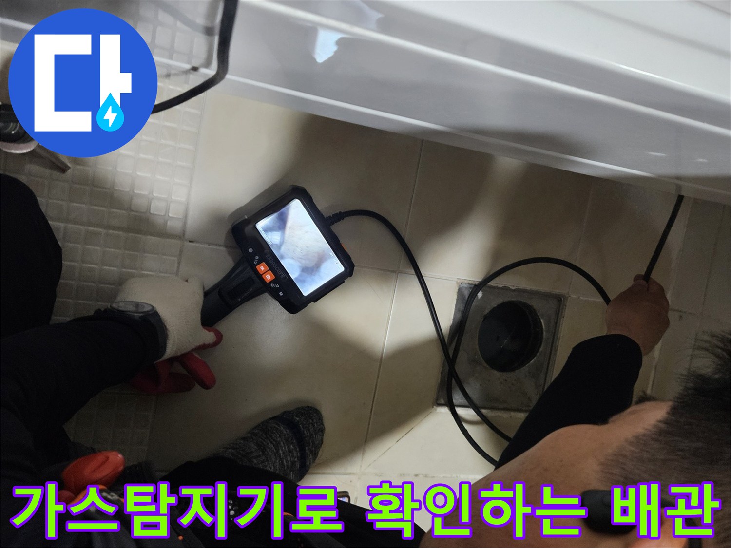 화장실 바닥에서 가스 탐지기를 사용하여 배관 상태를 점검하는 모습