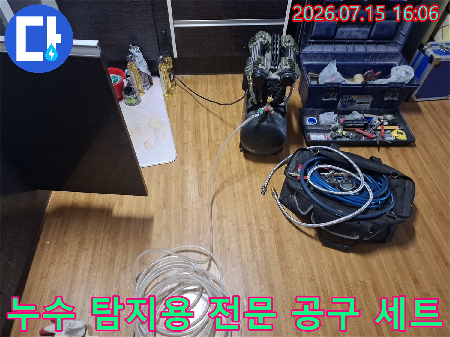 바닥에 펼쳐진 누수 탐지 장비-압력 탱크-파란색 호스 뭉치-정밀 수공구함
