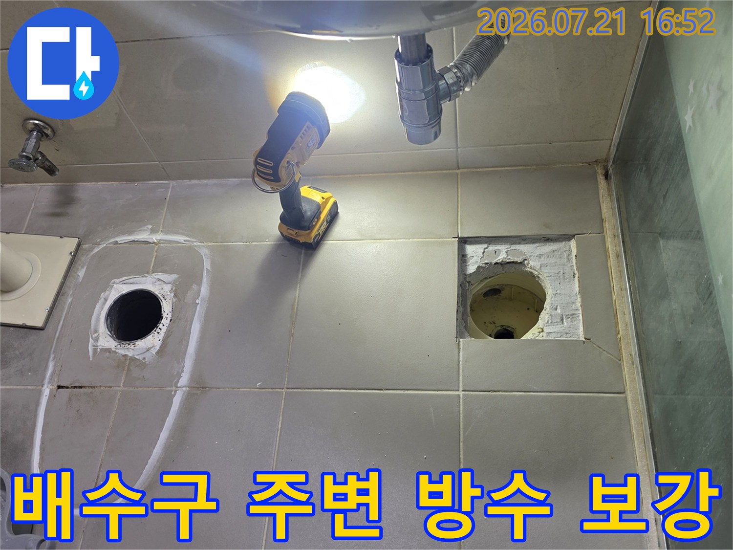 배수구 주변의 타일 제거 후 노출된 배관과 공구가 있는 모습