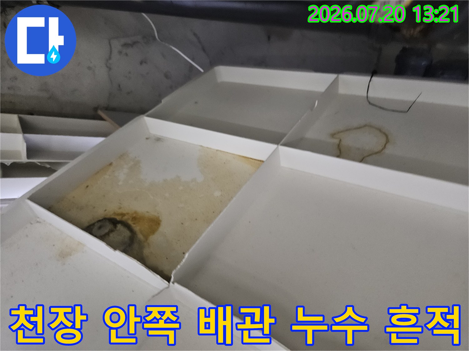 누수로 인해 변색된 천장 마감재와 노출된 배관 연결부 모습