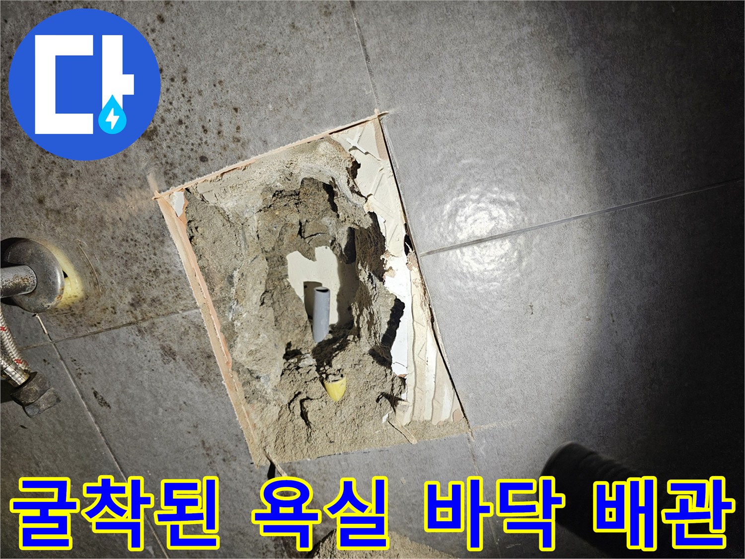 타일 아래 드러난 수도 배관과 콘크리트 층