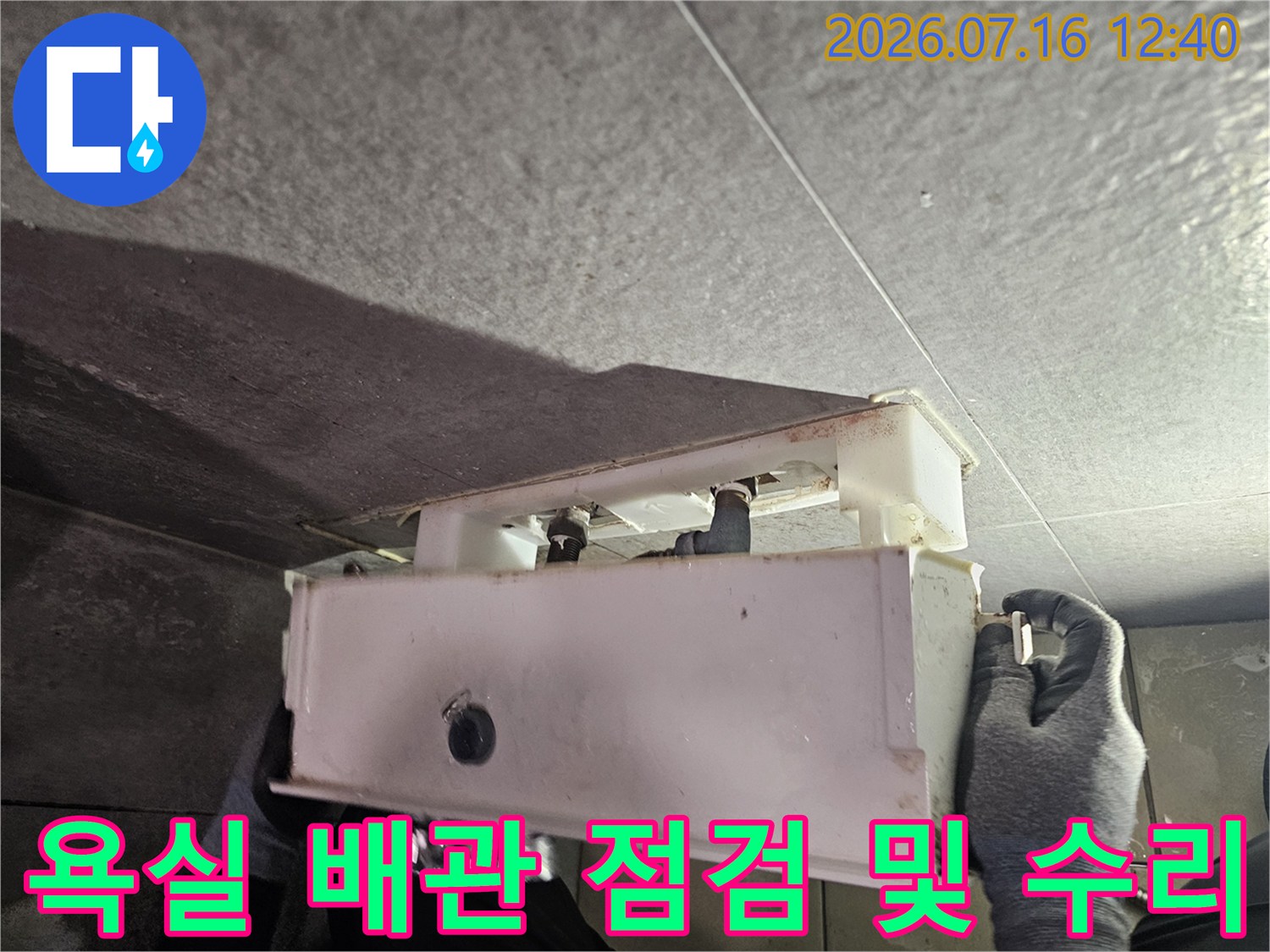 타일을 제거하고 노출된 하얀색 배관 부위를 점검하는 작업 현장