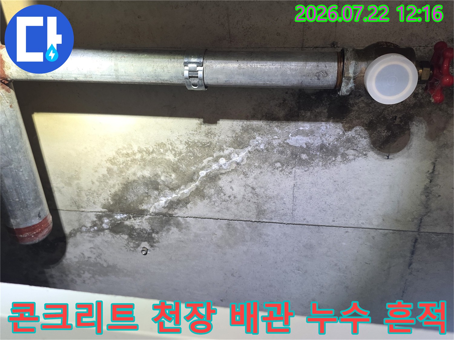 금속 배관 하단 콘크리트 벽면에 물이 흘러내린 자국과 곰팡이가 형성된 모습