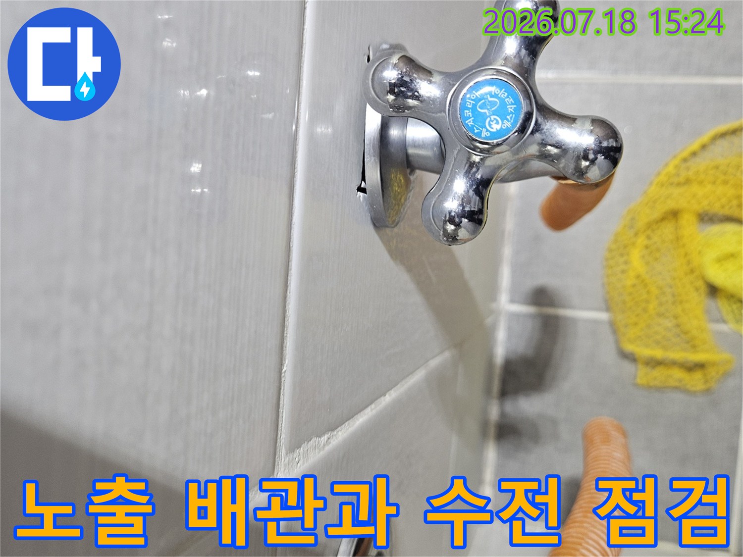 오렌지색 보온재로 보호된 배관과 화장실용 십자형 수전의 근접 촬영