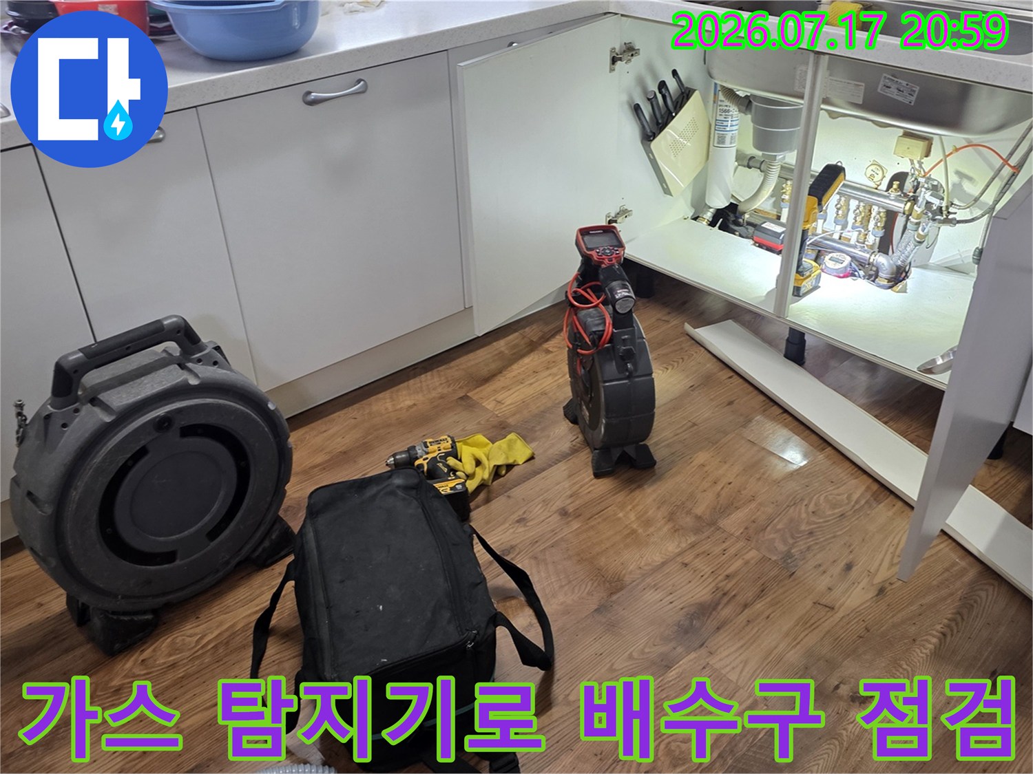 가스 누출 감지기를 사용하여 싱크대 하부의 배수 트랩과 연결 부위를 점검하는 모습