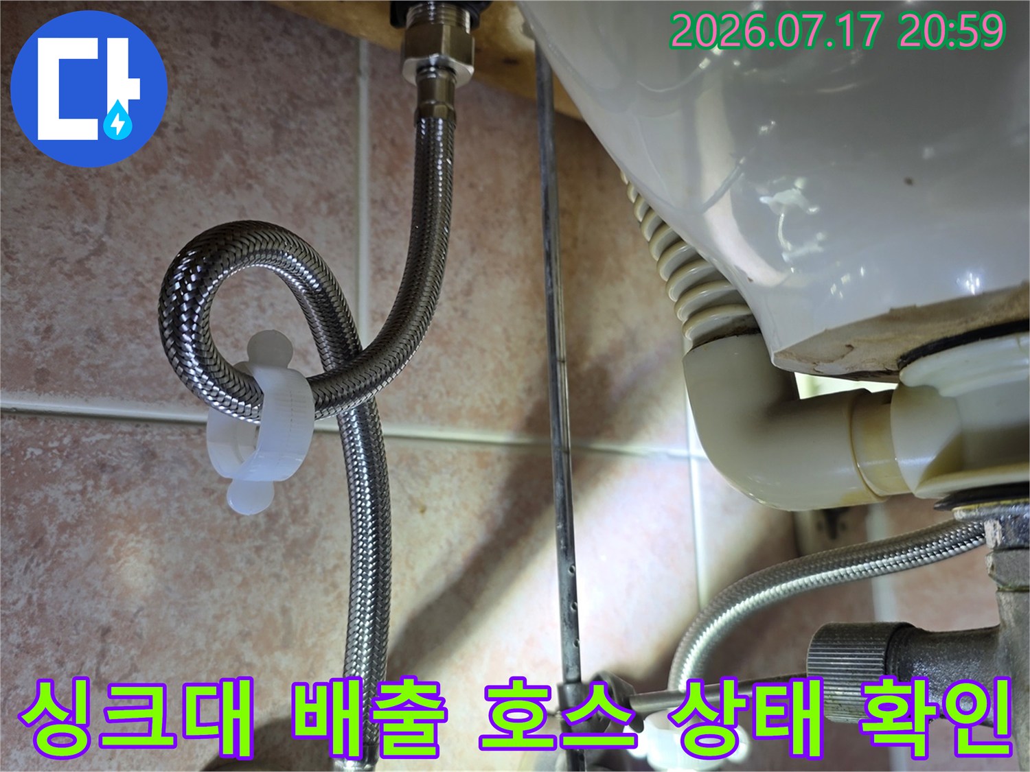 싱크대 하부 공간에서 주름형 배수 호스와 연결 트랩의 이상 여부를 살피는 장면