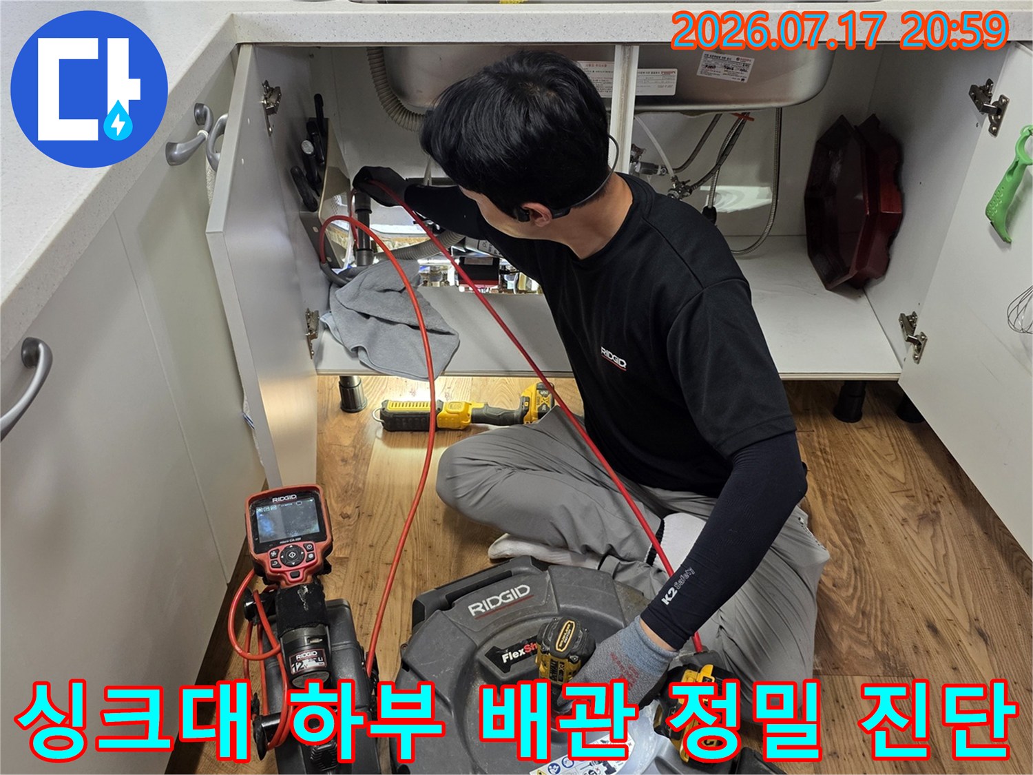 싱크대를 제거하고 노출된 아래쪽 공간에서 전문 장비로 배수 상태를 점검하는 모습