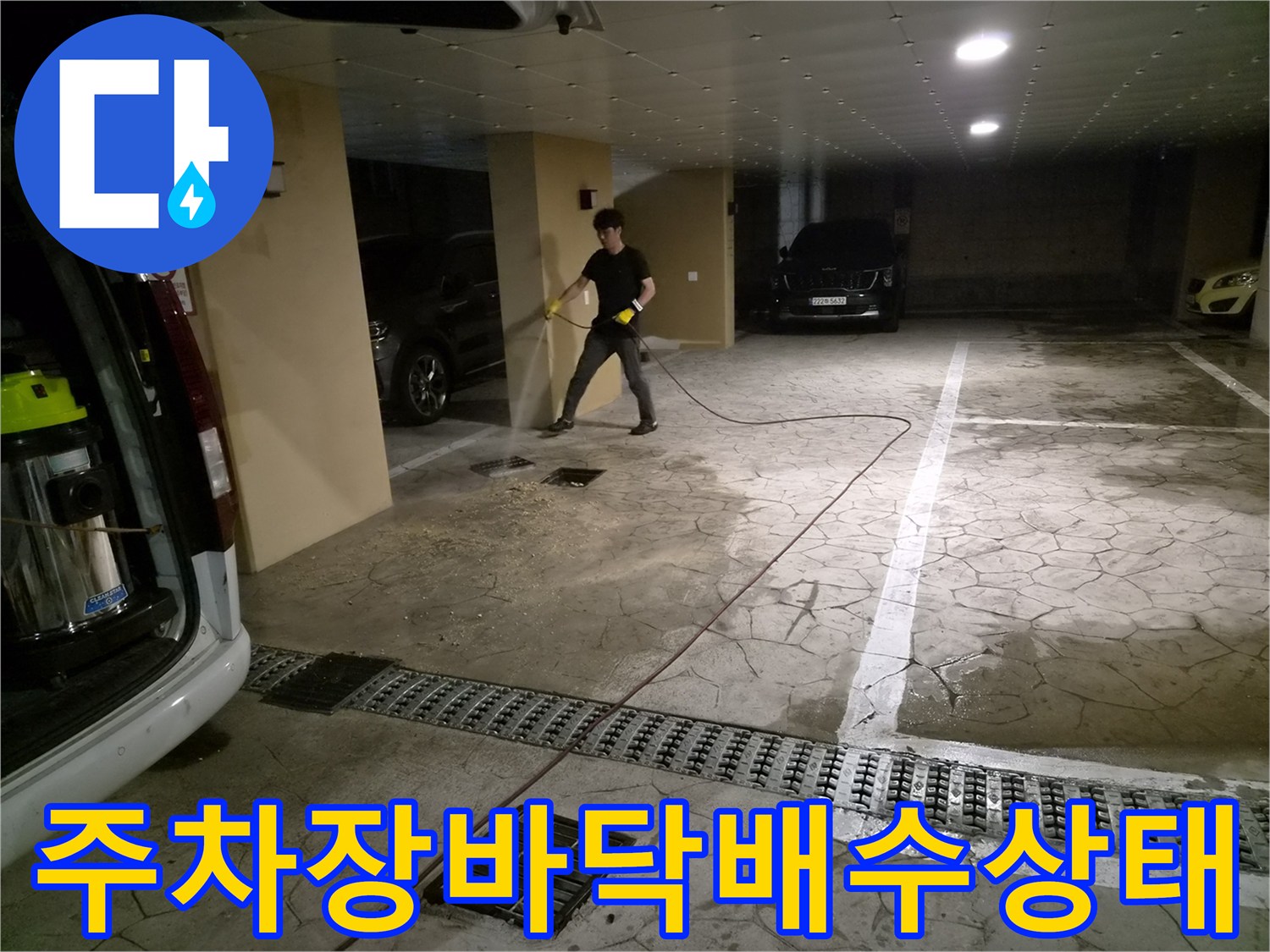 필로티 주차장 바닥의 젖은 구간과 작업 중인 전문가의 모습