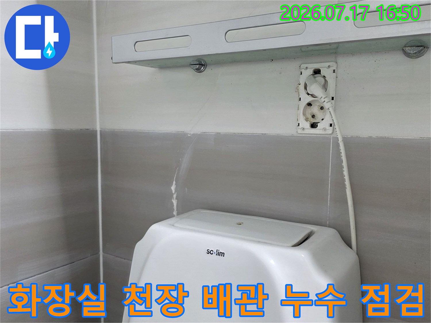화장실 천장 내부의 노출된 전선과 배관 주변을 조사하는 모습