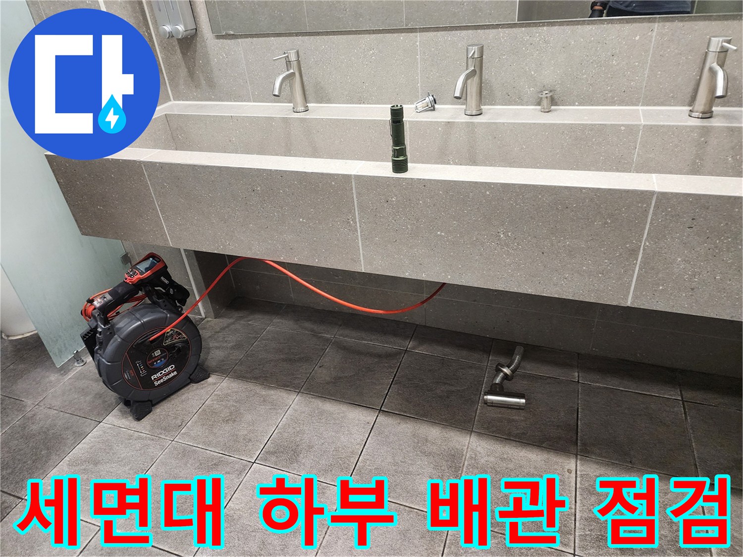 신촌 화장실 세면대 아래쪽 배관과 점검용 장비 모습