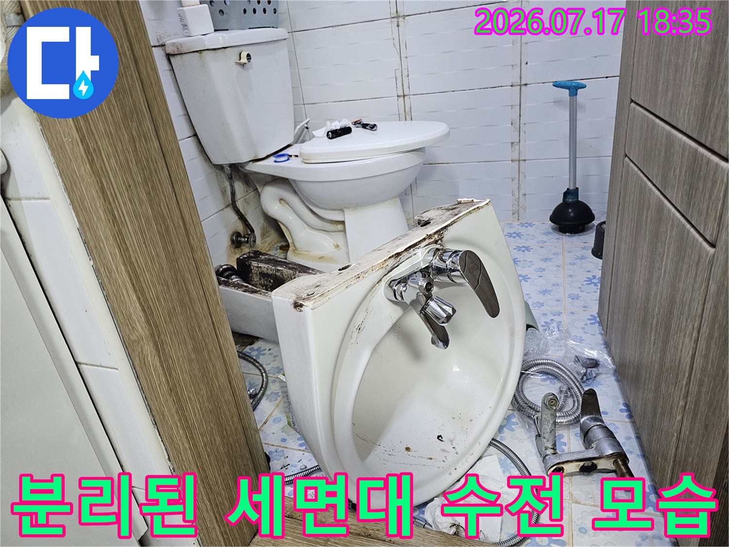바닥에 놓인 도기제 세면대-금속제 수전과 연결 호스가 함께 보임