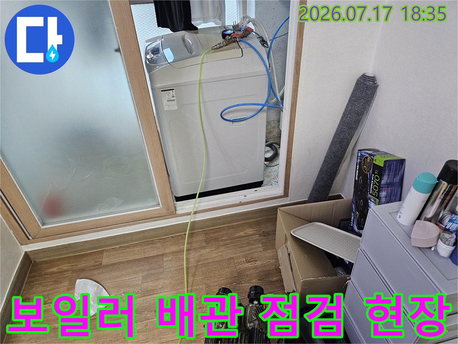 보일러 본체 상단 배관 연결 부위와 노란색 및 파란색 호스가 연결된 모습
