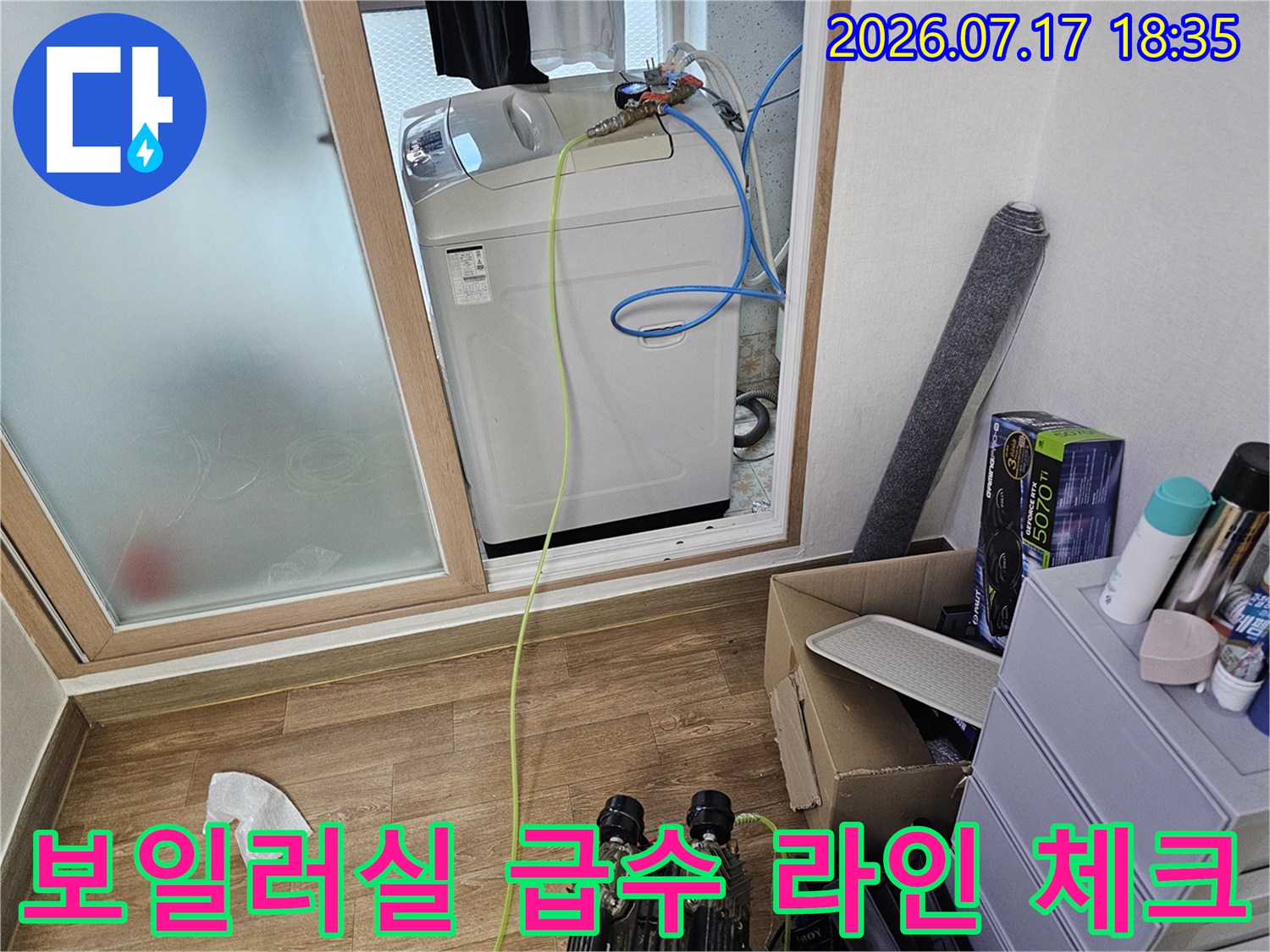 흰색 보일러 본체와 그 위에 연결된 파란색 배관-작업 중인 현장 사진