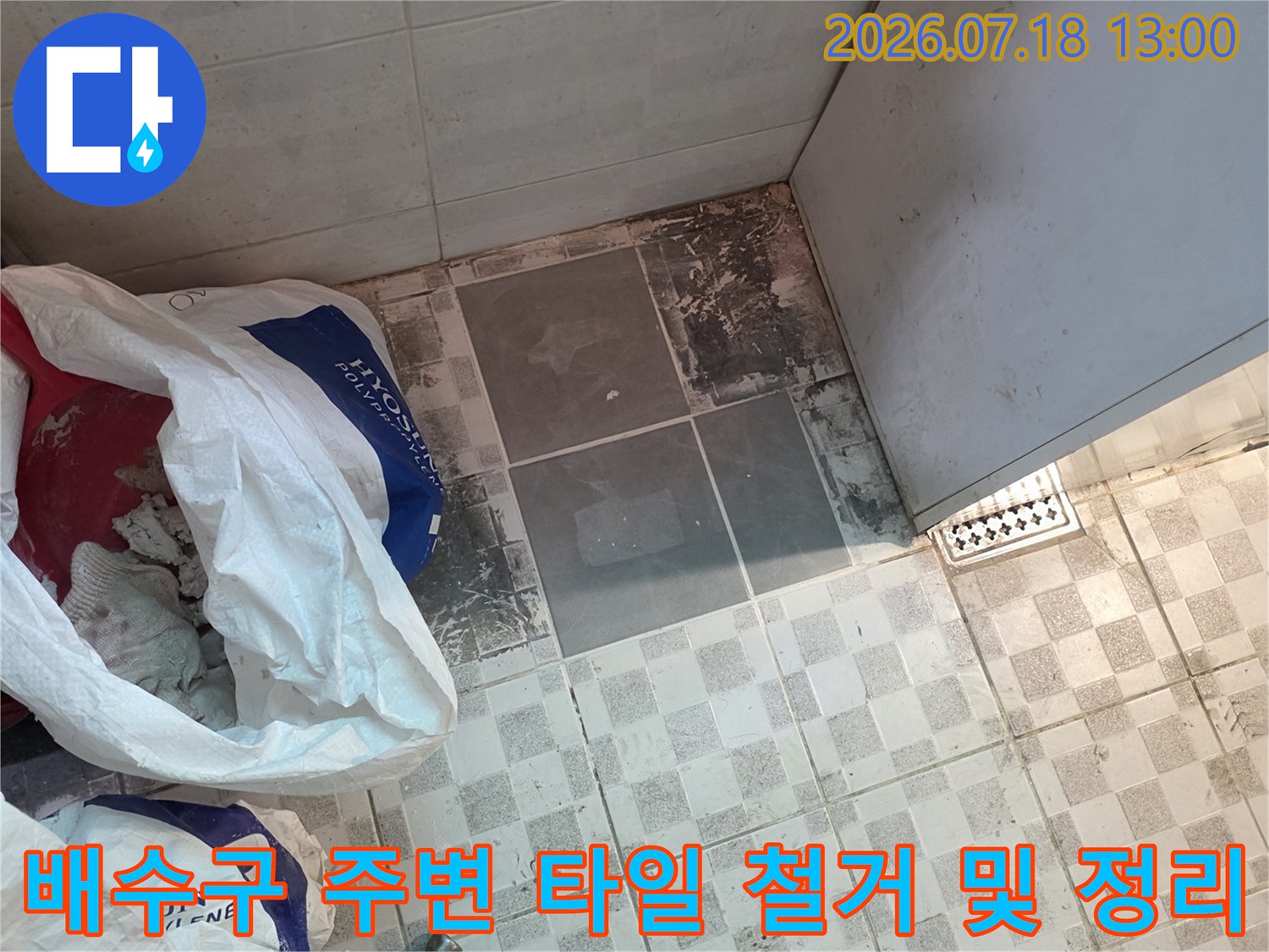 누수가 의심되는 배수구 쪽 타일을 제거하고 청소 도구를 배치한 현장 모습