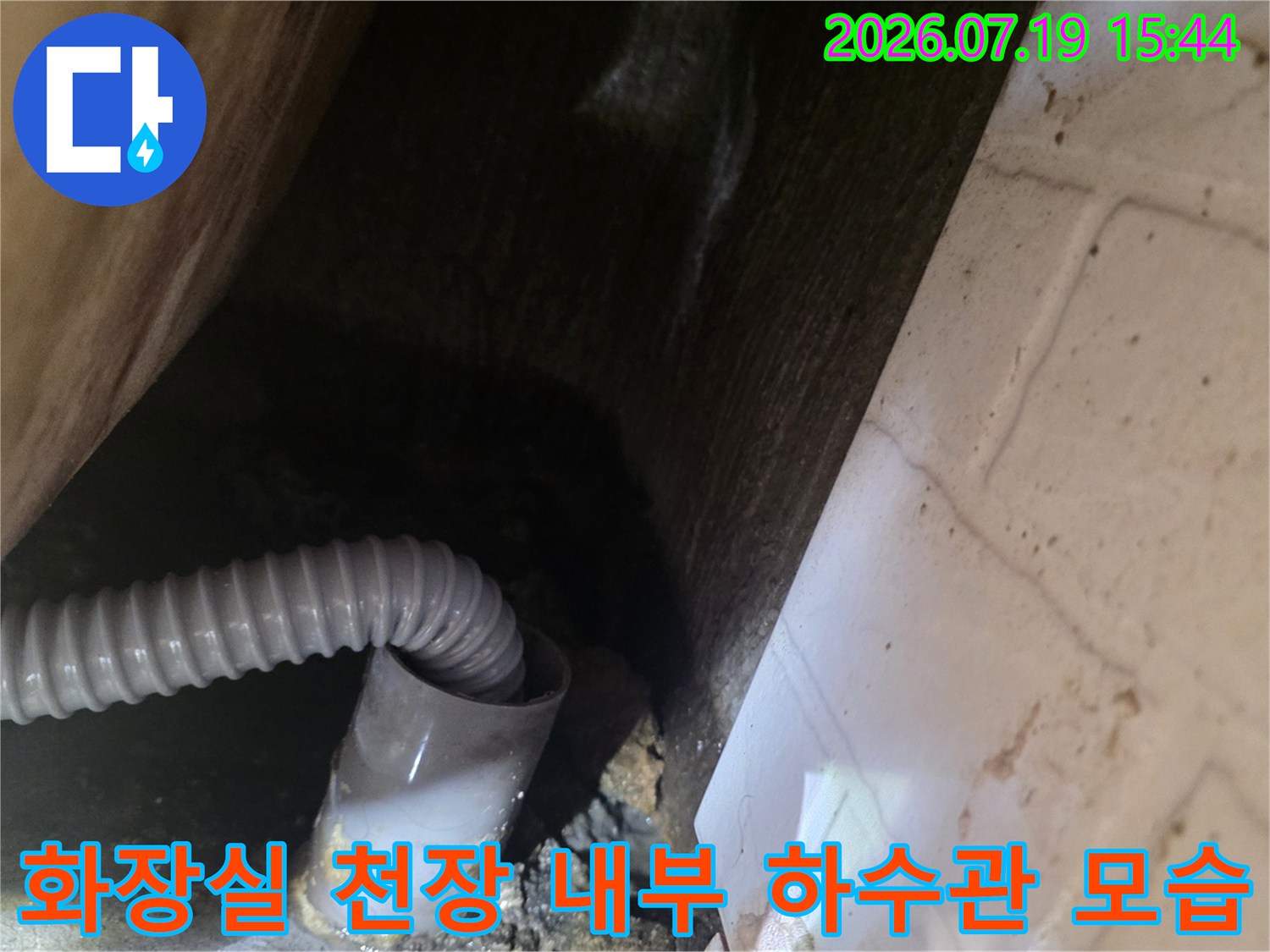 회색 주름관 배관이 설치된 화장실 천장 내부의 어두운 공간 사진