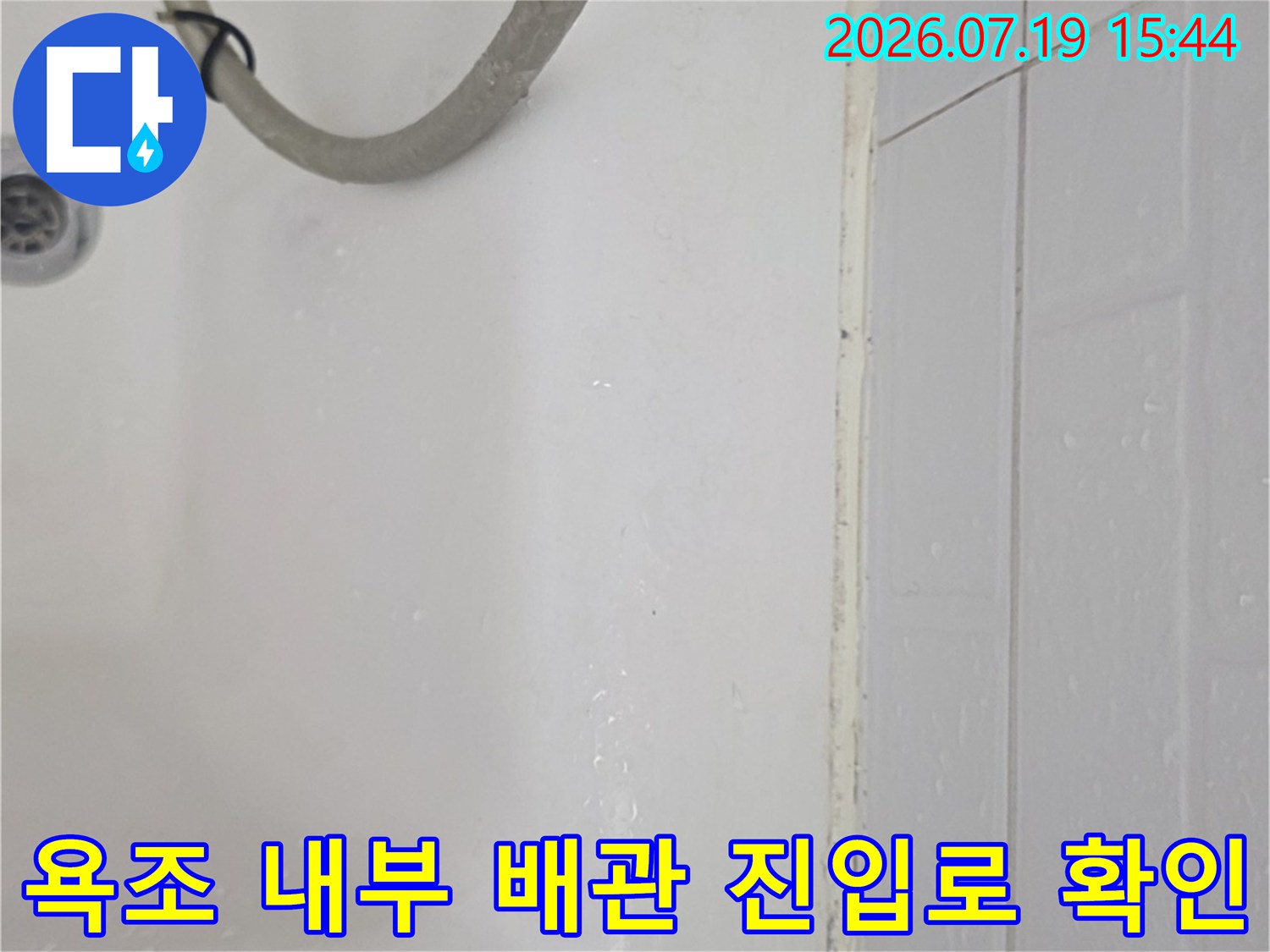 흰색 욕조-샤워 호스가 가로놓인 상태에서 배수구가 보임