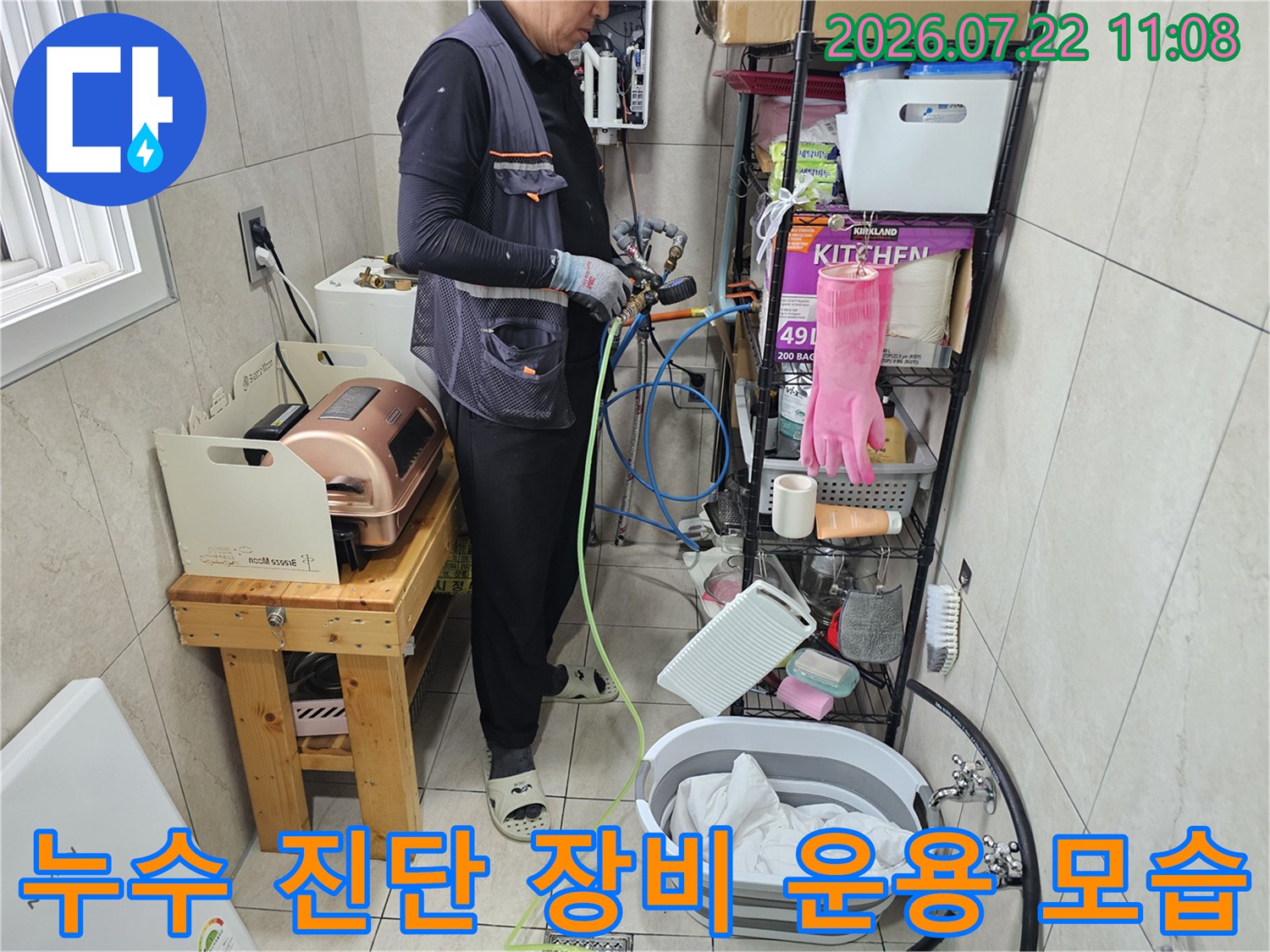 파란색 호스가 연결된 탐지기를 조작하며 배관의 누수 지점을 특정하고 있는 엔지니어의 손길