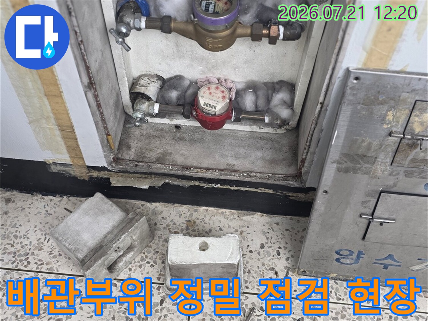 베란다 배관 주변에 위치한 계량기와 밸브를 세밀하게 살피는 모습