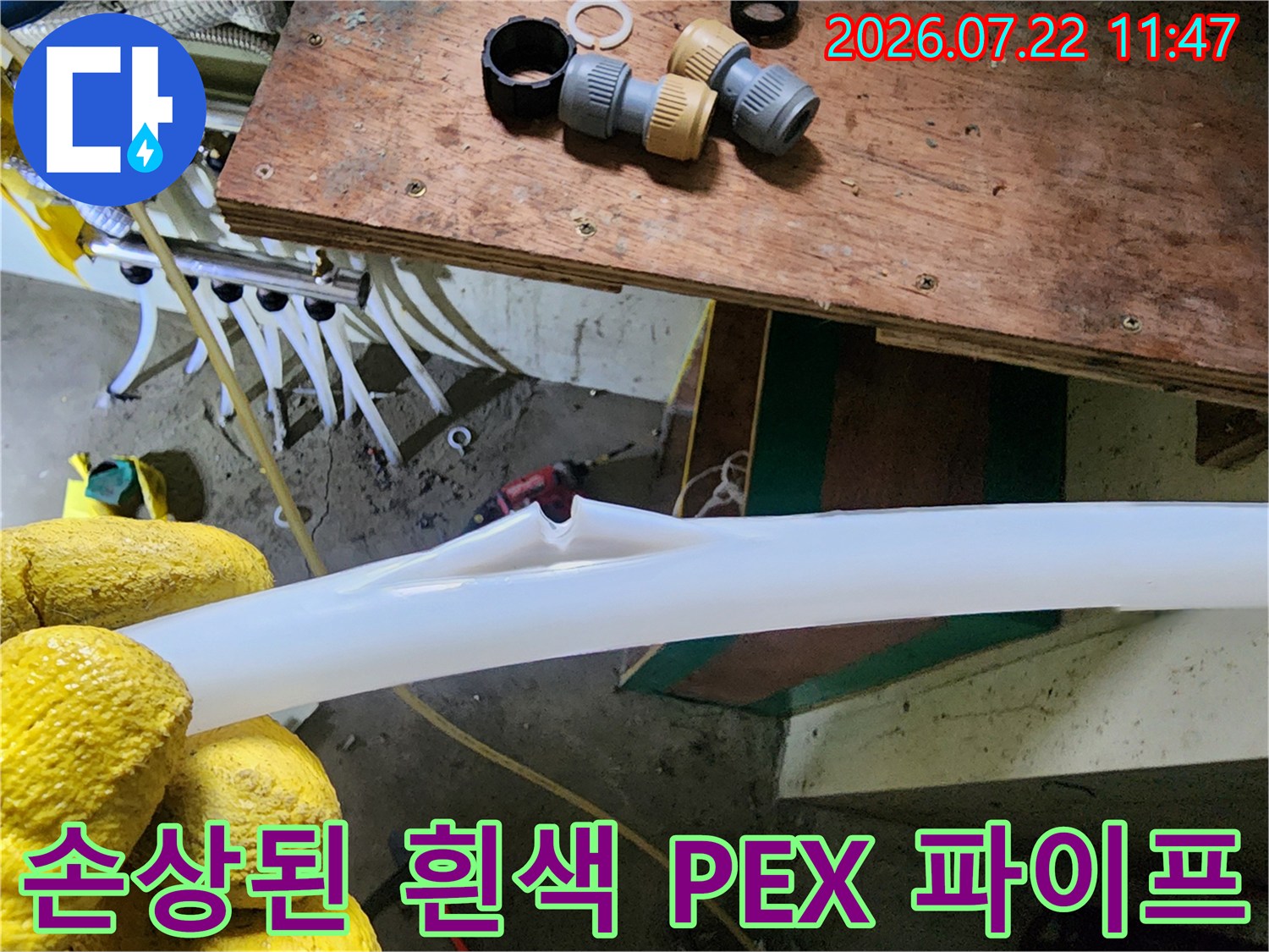 노란 작업 장갑을 낀 상태로 찢어진 부위가 드러난 흰색 보일러 배관을 잡고 있는 모습