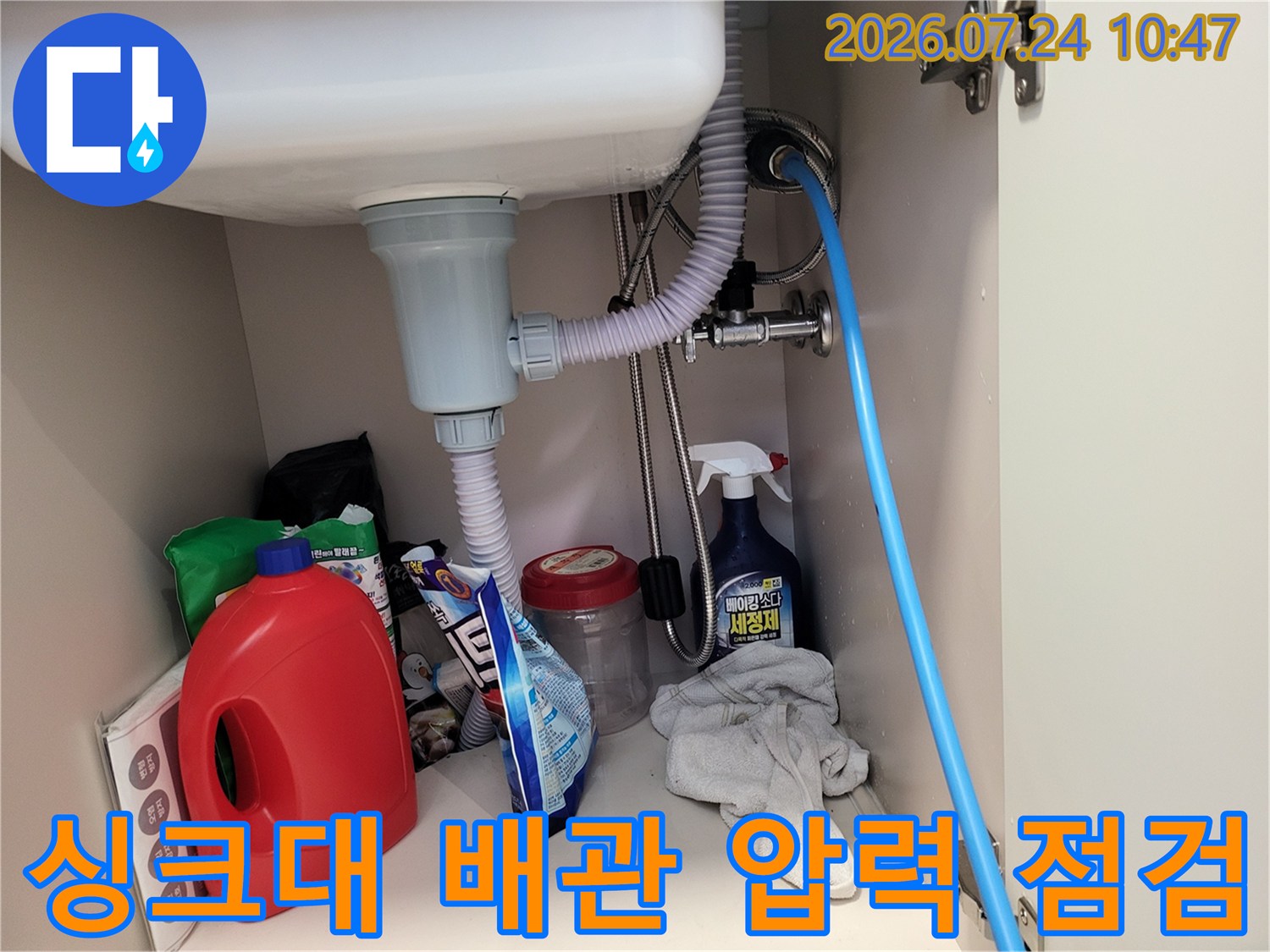 싱크대 하부 배관에 공기압 측정 호스를 연결하여 정밀 점검을 수행하는 모습