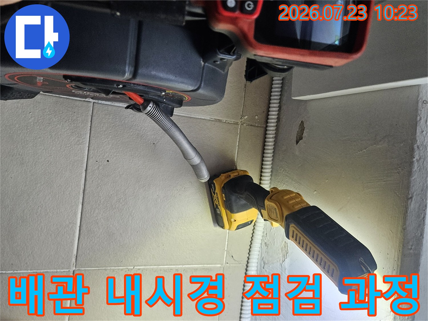 작업자가 누수 탐지용 모니터와 라이트를 사용하여 배관 주변을 살피는 장면