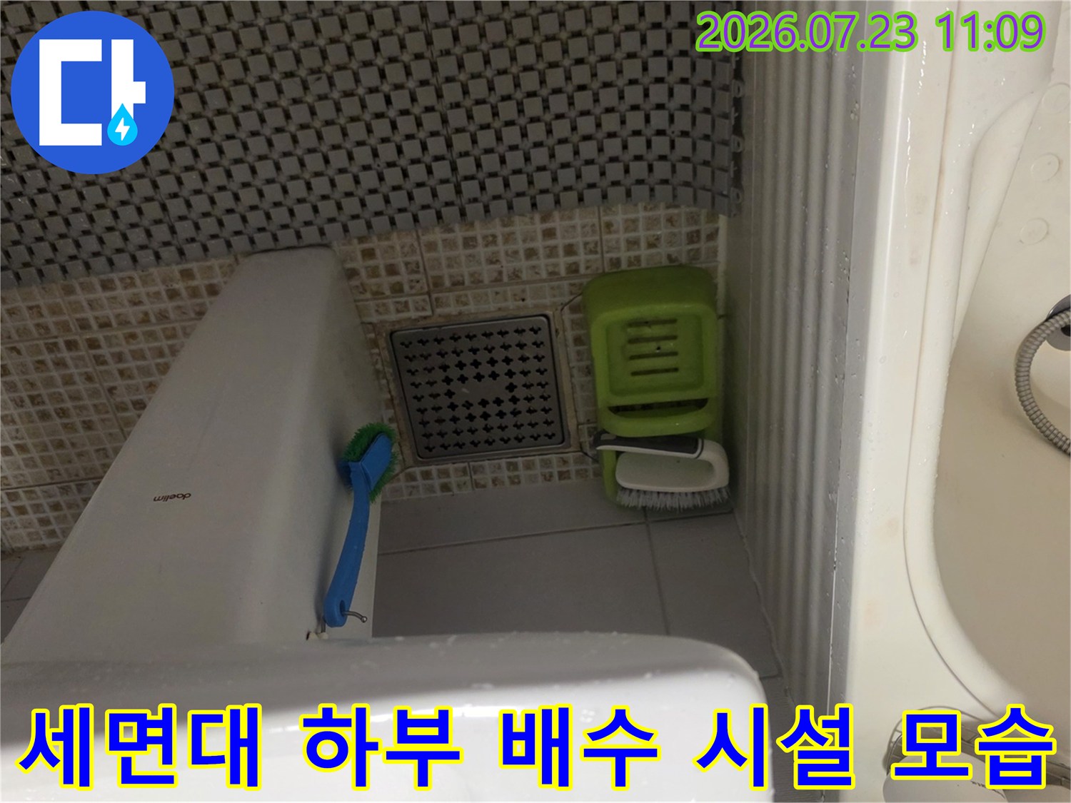 세면대-다리-옆으로-배치된-배수구와-청소용품들이-찍힌-사진