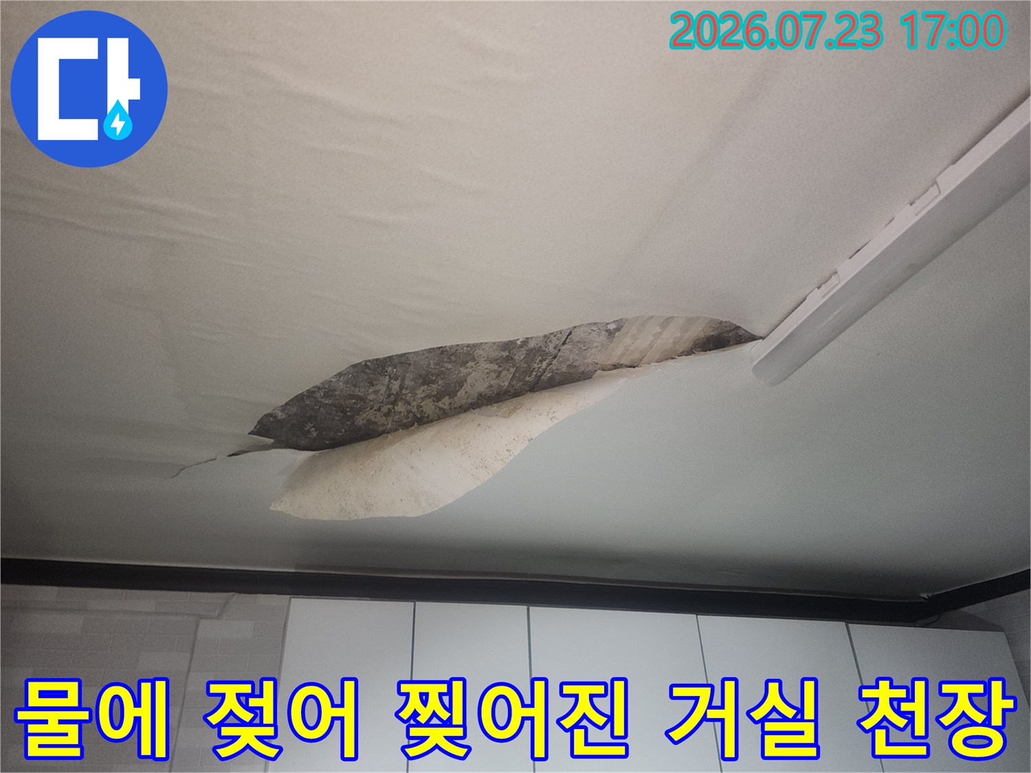 천장 실크벽지가 누수로 인해 젖어서 일부가 찢어지고 내부 콘크리트 층이 드러난 모습