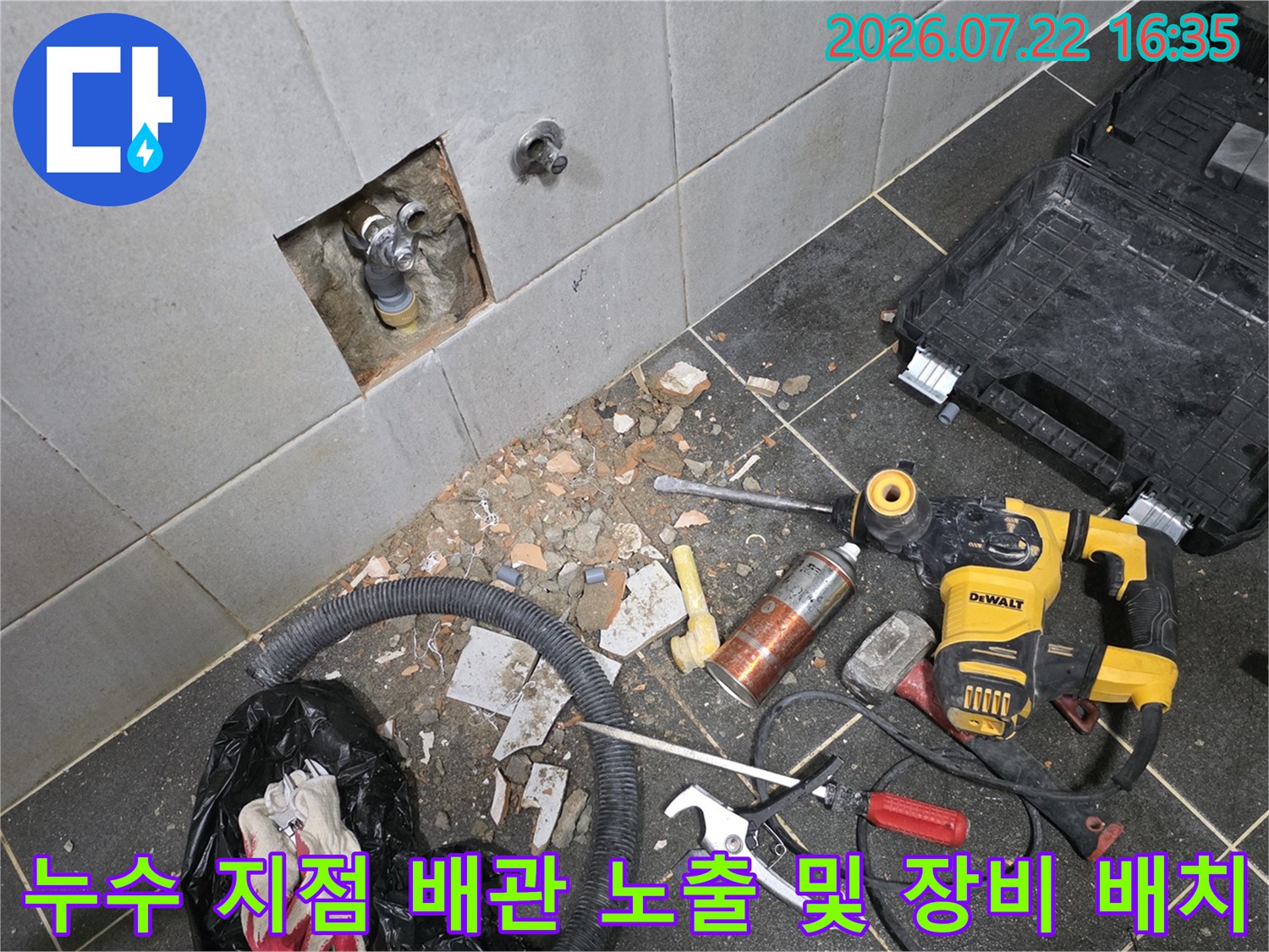 굴착된 벽면 배관 주변으로 전동드릴과 렌치 등 전문 공구들이 놓여 있는 모습