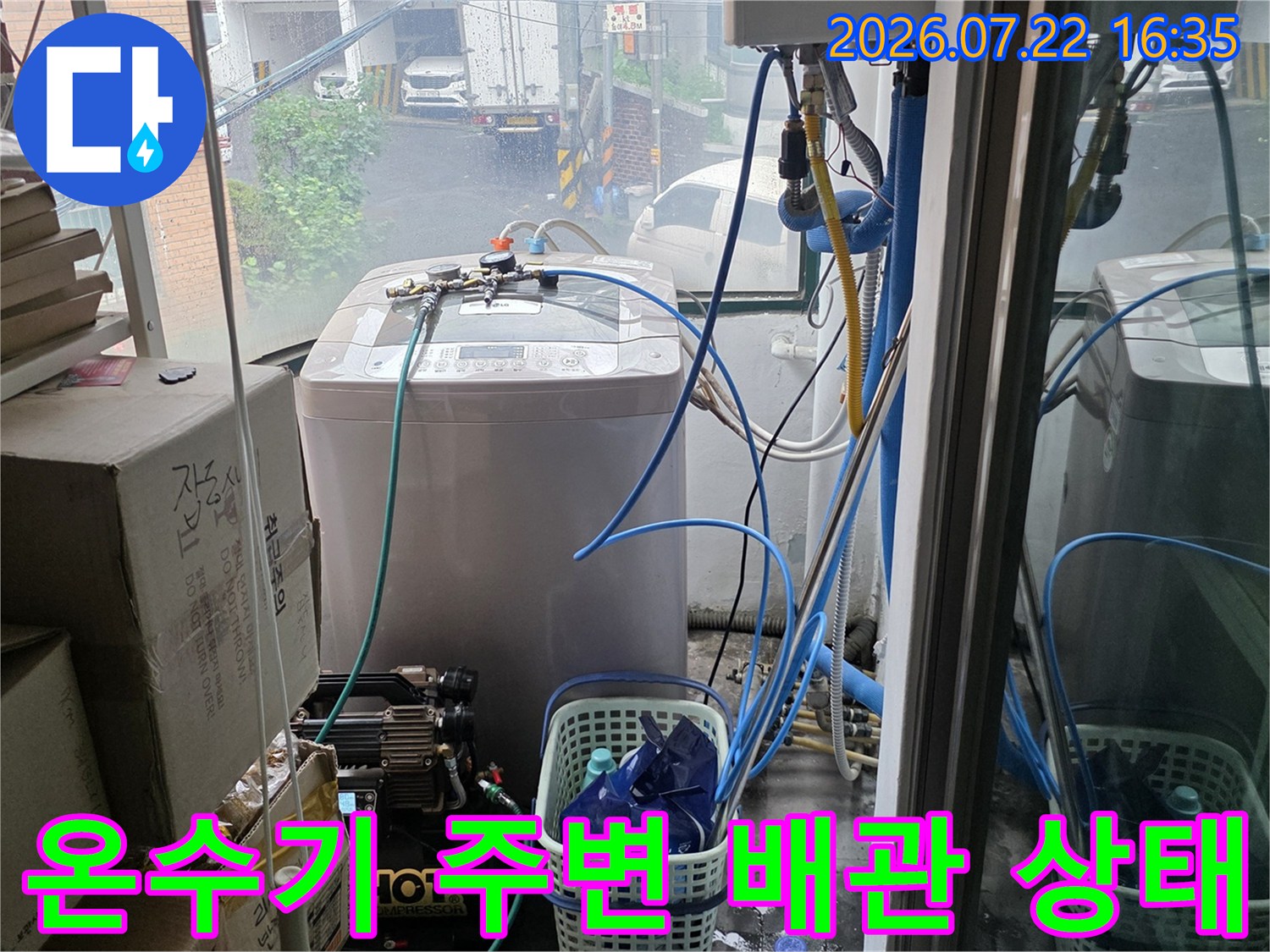 흰색 가전 장비 위로 연결된 파란색 플라스틱 배관과 바닥의 정리함