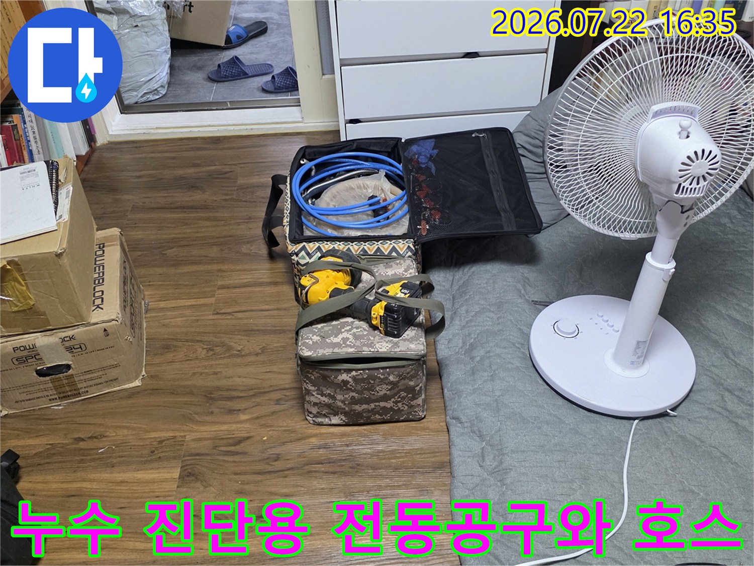 흰색 선풍기 옆에 준비된 파란색 배관 검사용 호스와 노란색 전동 드릴