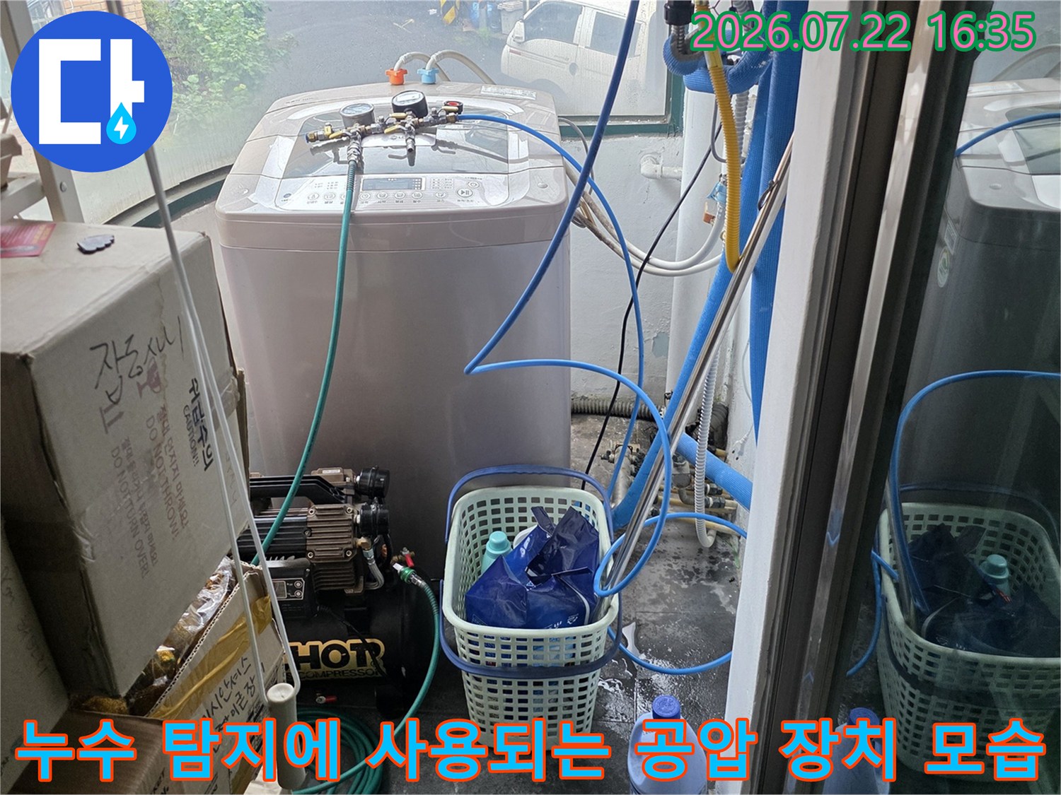 흰색 세탁기 옆에 배치된 파란색 호스 기반의 누수 탐지 장비-진단 과정