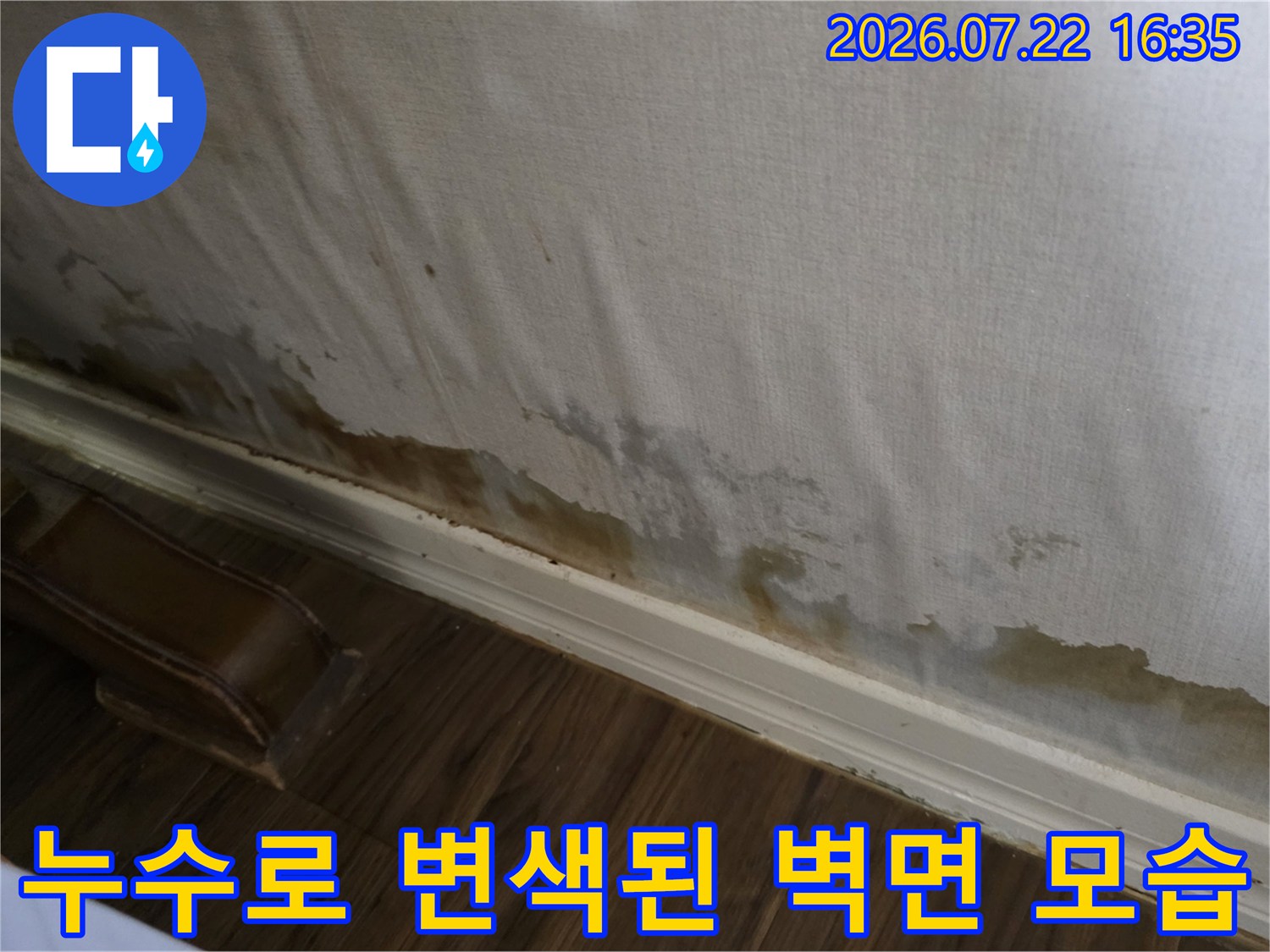 흰색 실크벽지 하단에 갈색의 누수 얼룩과 곰팡이가 번져있는 모습