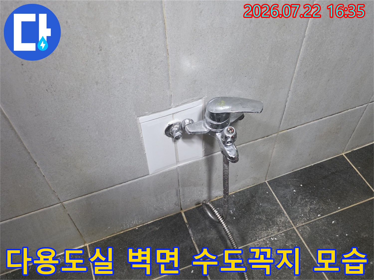 흰색 타일 벽면에 설치된-은색 금속 재질의 수도꼭지와 연결 호스