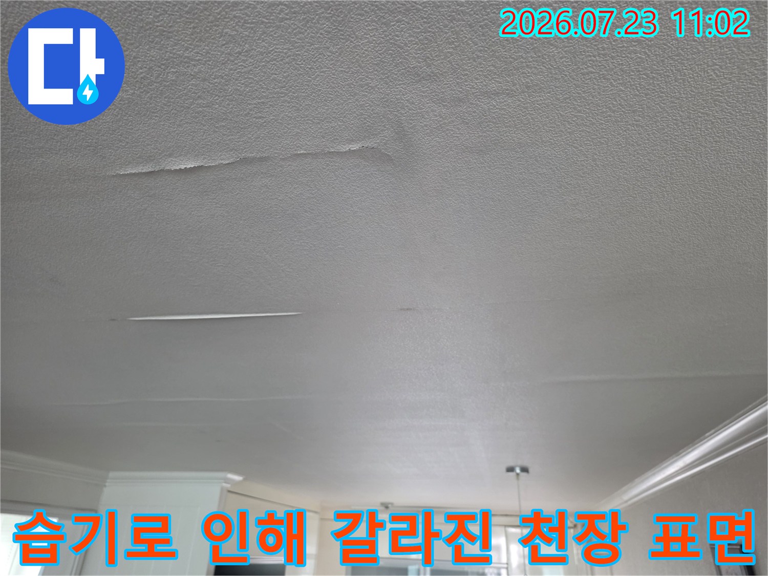 흰색 텍스처의 천장 마감재가 습기 침투로 인해 가늘게 균열이 생기고 들떠 있는 사진
