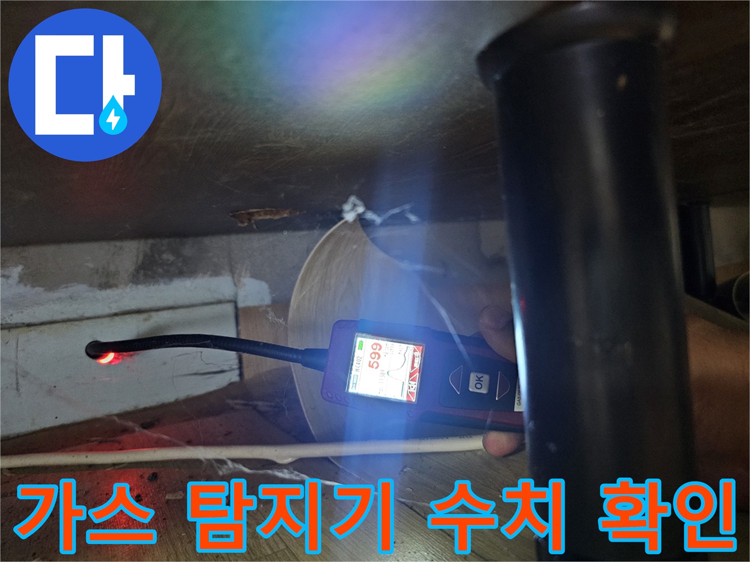 싱크대 하단 좁은 공간에서 가스 탐지기로 배관 누수 지점을 추정하는 모습입니다.