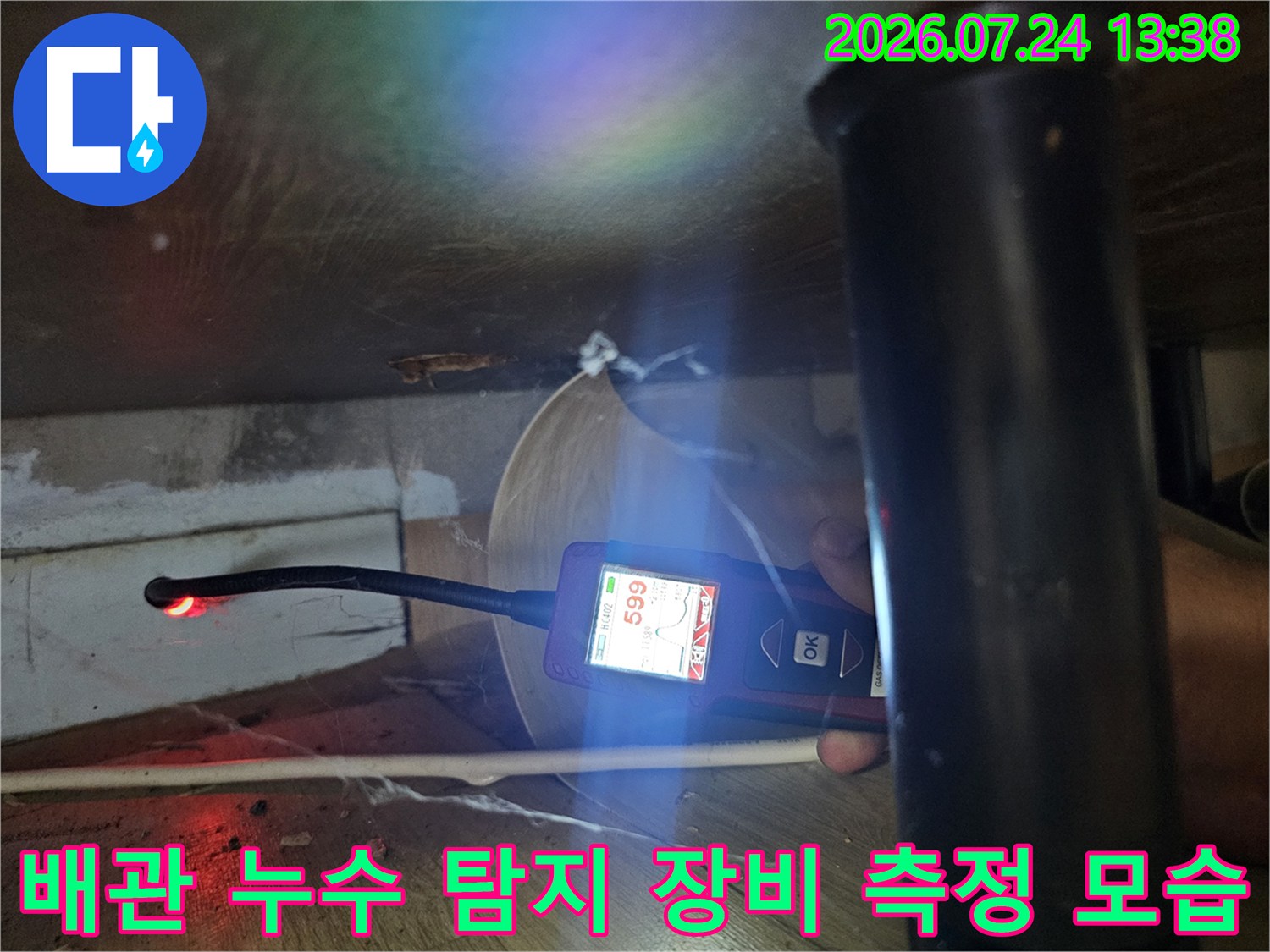 어두운 가구 하단 공간에서 가스 탐지기로 누수 여부를 세밀하게 점검하는 장면