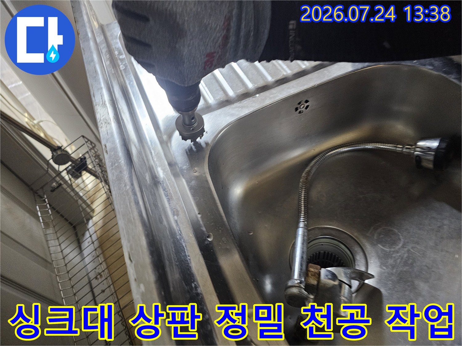 전동 공구를 사용하여 싱크대 스테인리스 볼 가장자리에 원형 구멍을 뚫고 있는 엔지니어의 손