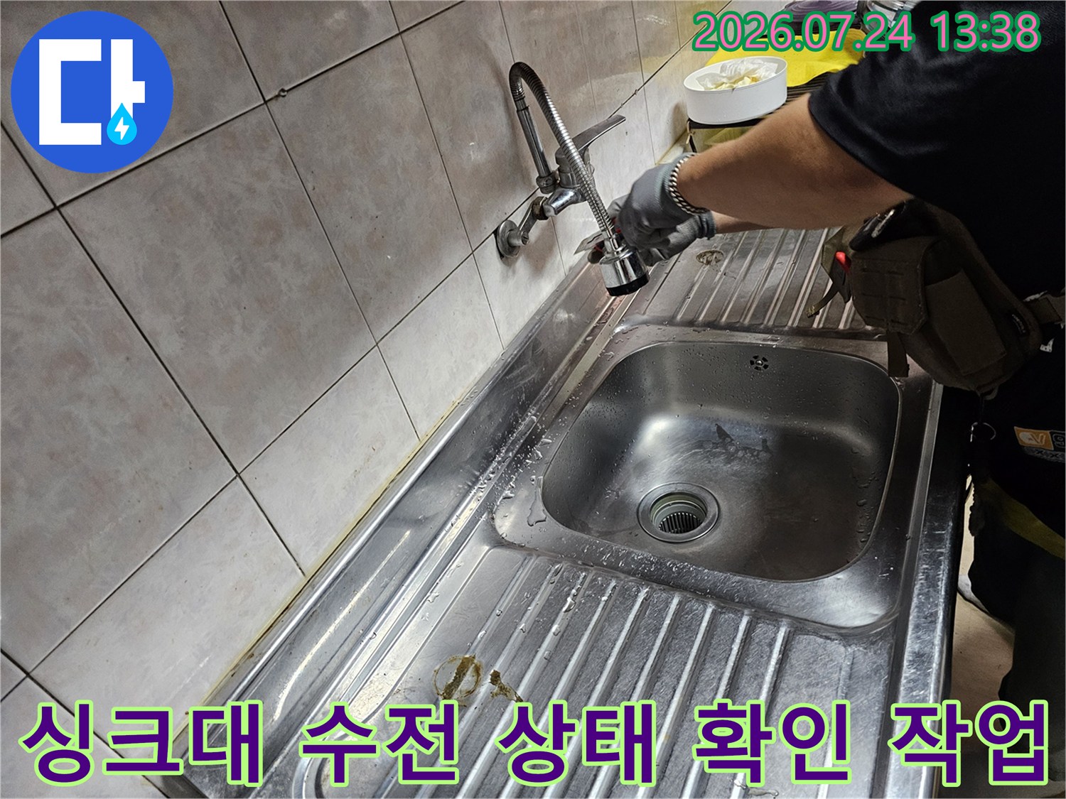 주방 싱크대에서 엔지니어가 수전 배관 연결 부위를 세밀하게 점검하는 모습