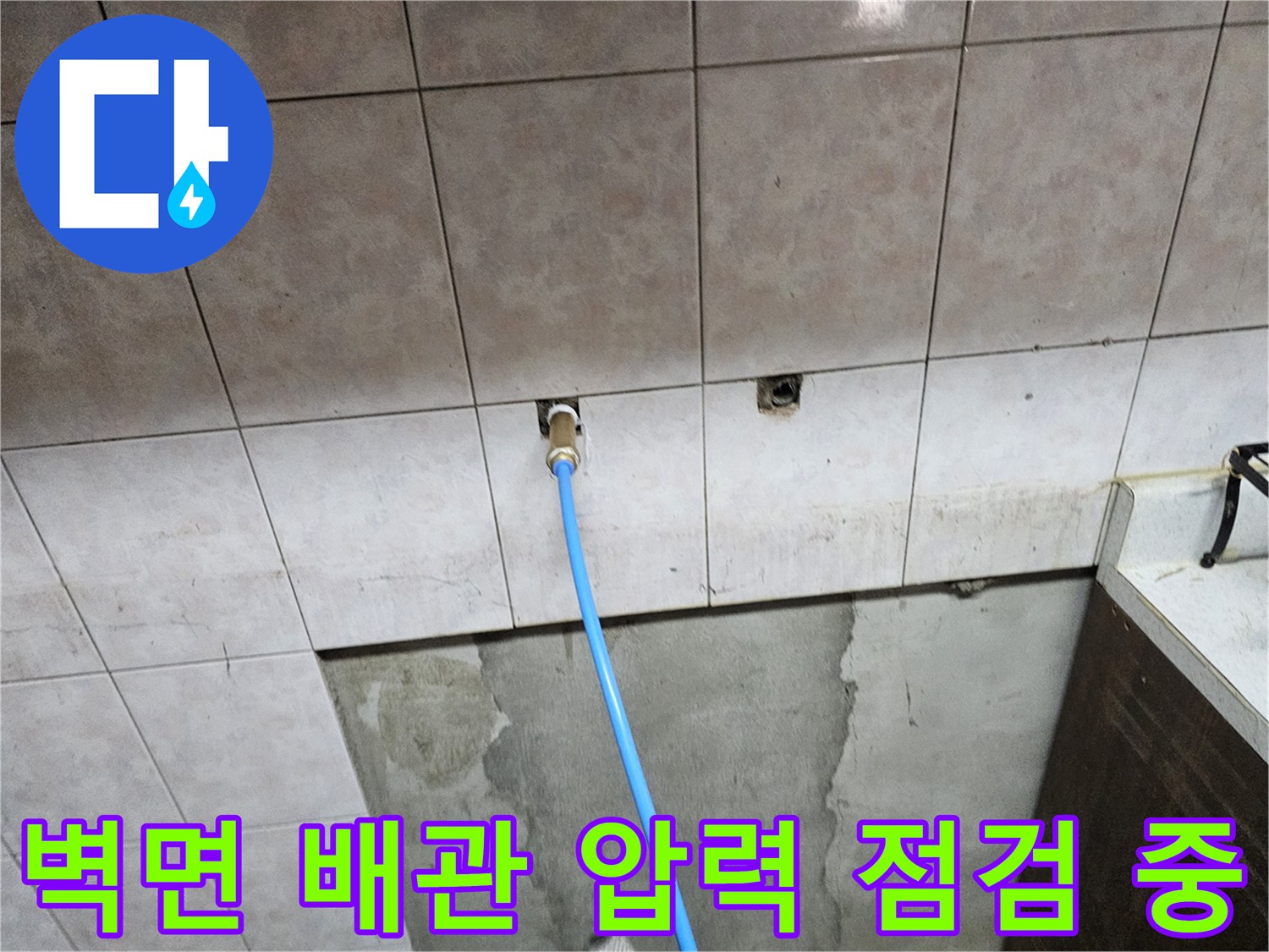 타일 벽면 배관 연결 부위와 파란색 호스 연결 상태