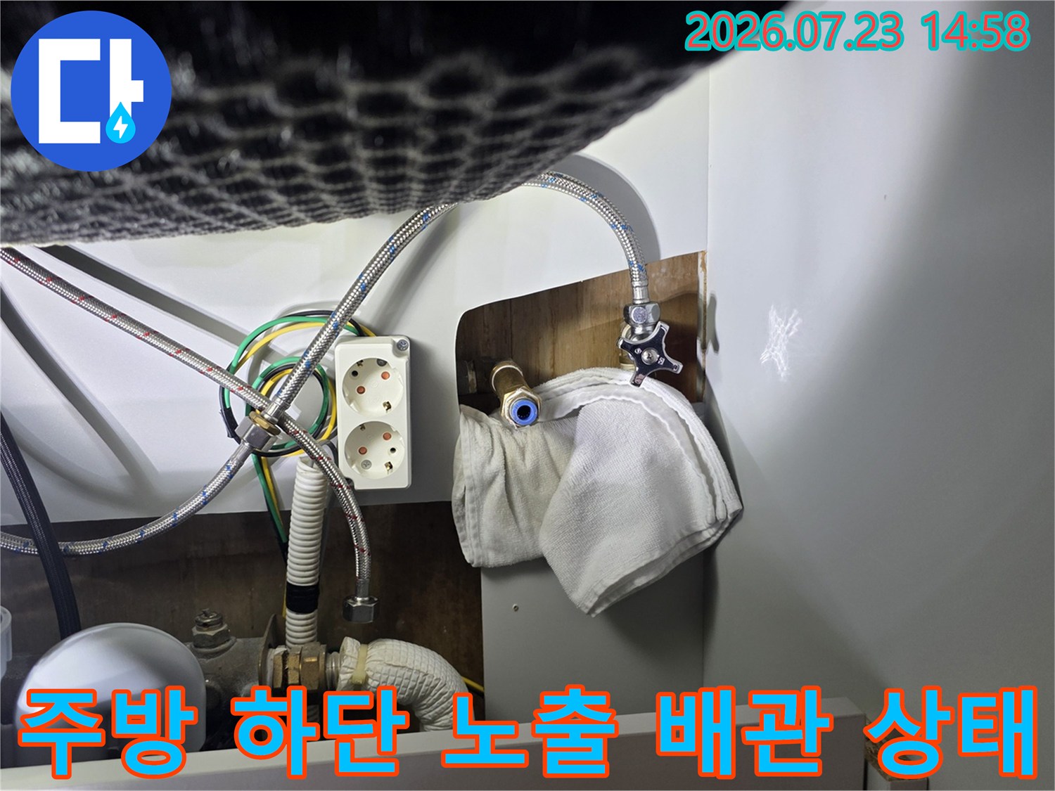흰색 천으로 덮인-싱크대 배관 연결 부위와 전기 콘센트 모습