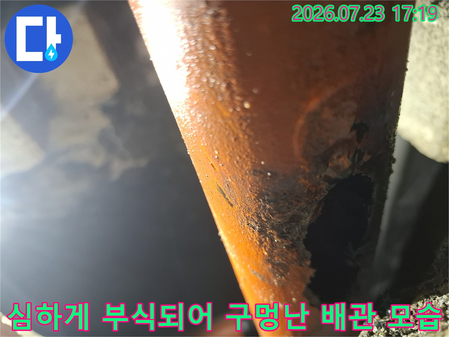 오렌지색 배관 외벽이 심하게 부식되어 커다란 구멍이 뚫려 있는 누수 현장 사진