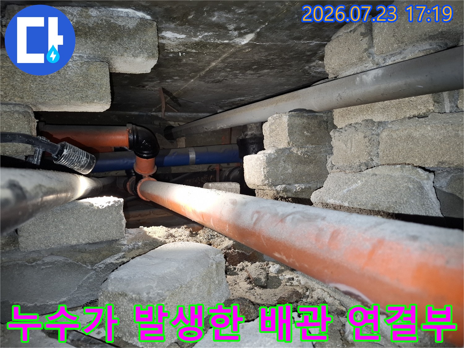 오렌지색-배관과-검은색 연결 부속이-콘크리트 천장 아래 설치된 모습